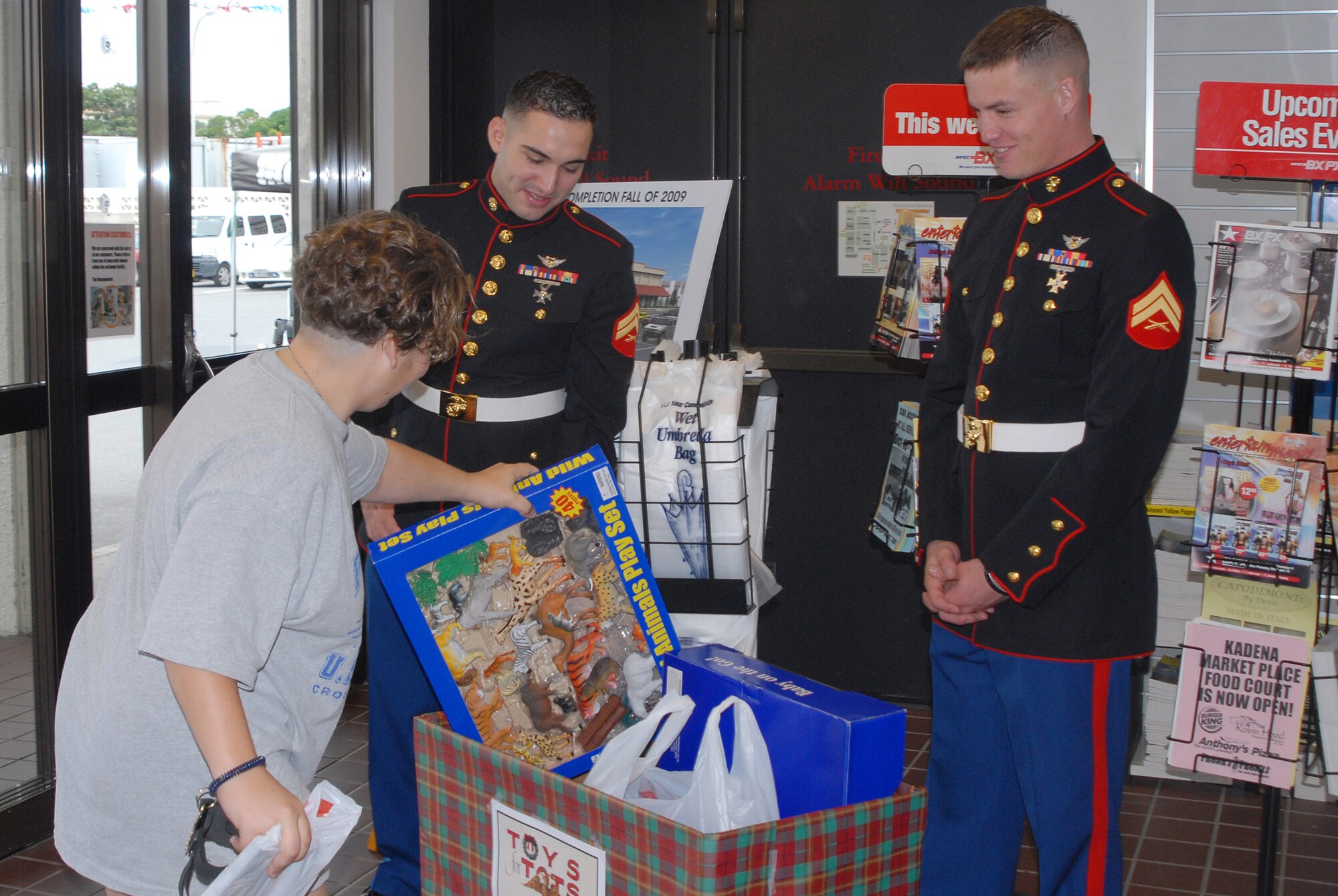 Cpl. Cody Bryant and Cpl. Kyle Cox receive a gift from a Kadena Base Exchange patron during the Toys for Tots drive. During the annual drive Marines collect toys for needy children all over the world. (U.S. Air Force photo/Airman 1st Class Ryan Ivacic)