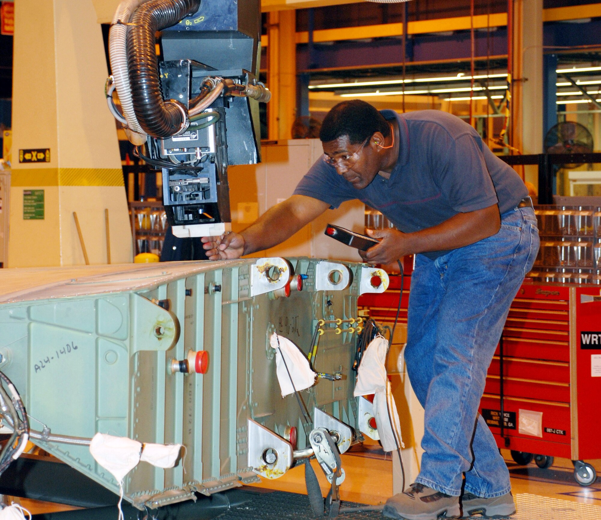 Gene Manns, Air Force sheet metal mechanic, programs the robotic machinery to remove screws from the top panel of an F-15 Eagle wing in the F-15 wing shop at Robins Air Force Base, Ga. (Defense Logistics Agency photo by Amy Clement) 
