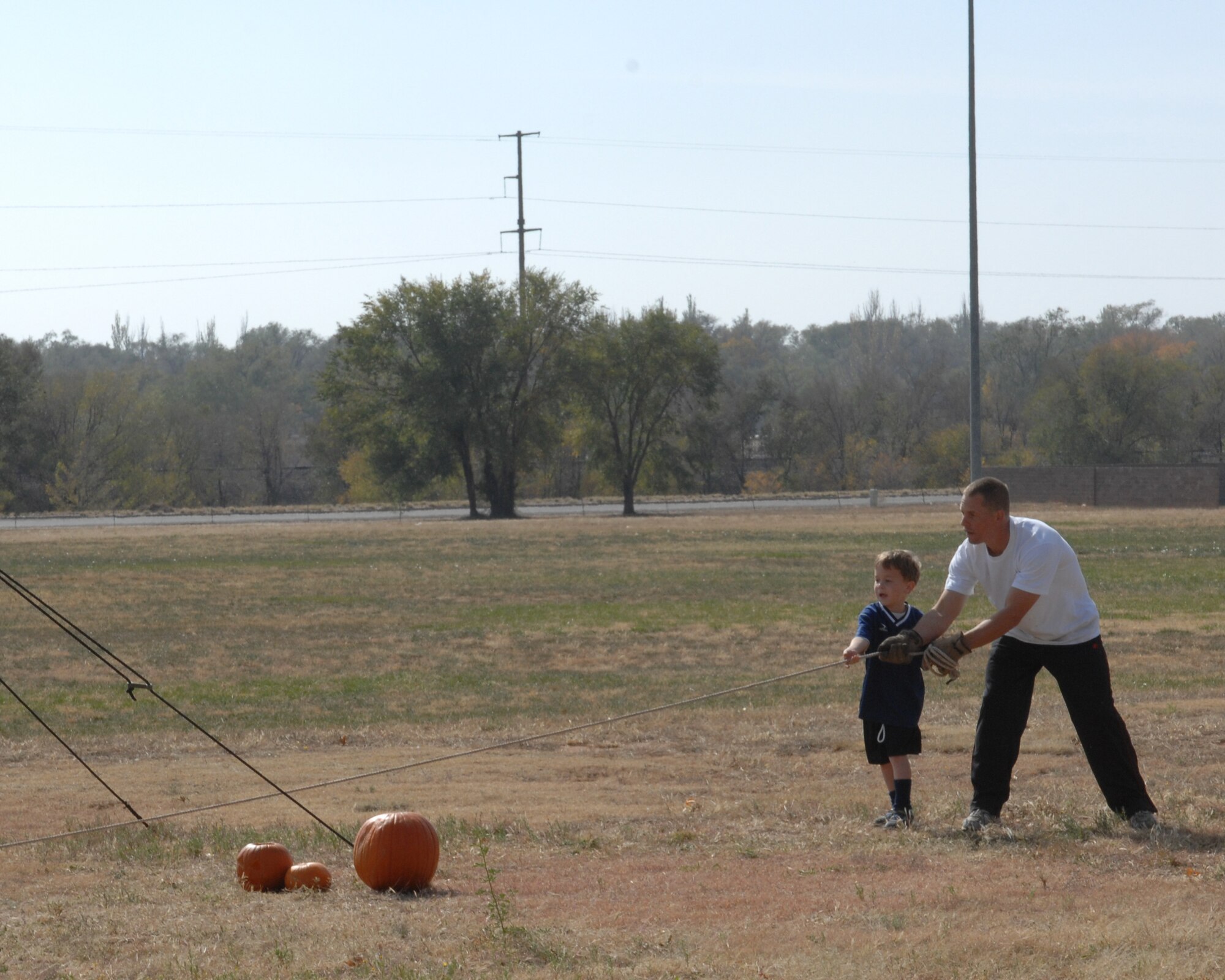 CANNON AIR FORCE BASE, N.M. -- Tech. Sgt. Jesse Hemsworth, 27th Special Operations Civil Engineering Squadron, and his son Ezra pull the catapult release rope to watch their pumpkin go flying. The Pumpkin Chunkin held Nov. 3 at Doc Stewart Park was a fun way for people to dispose of their leftover Halloween pumpkins. (U.S. Air Force photo by Airman 1st Class Evelyn Chavez)