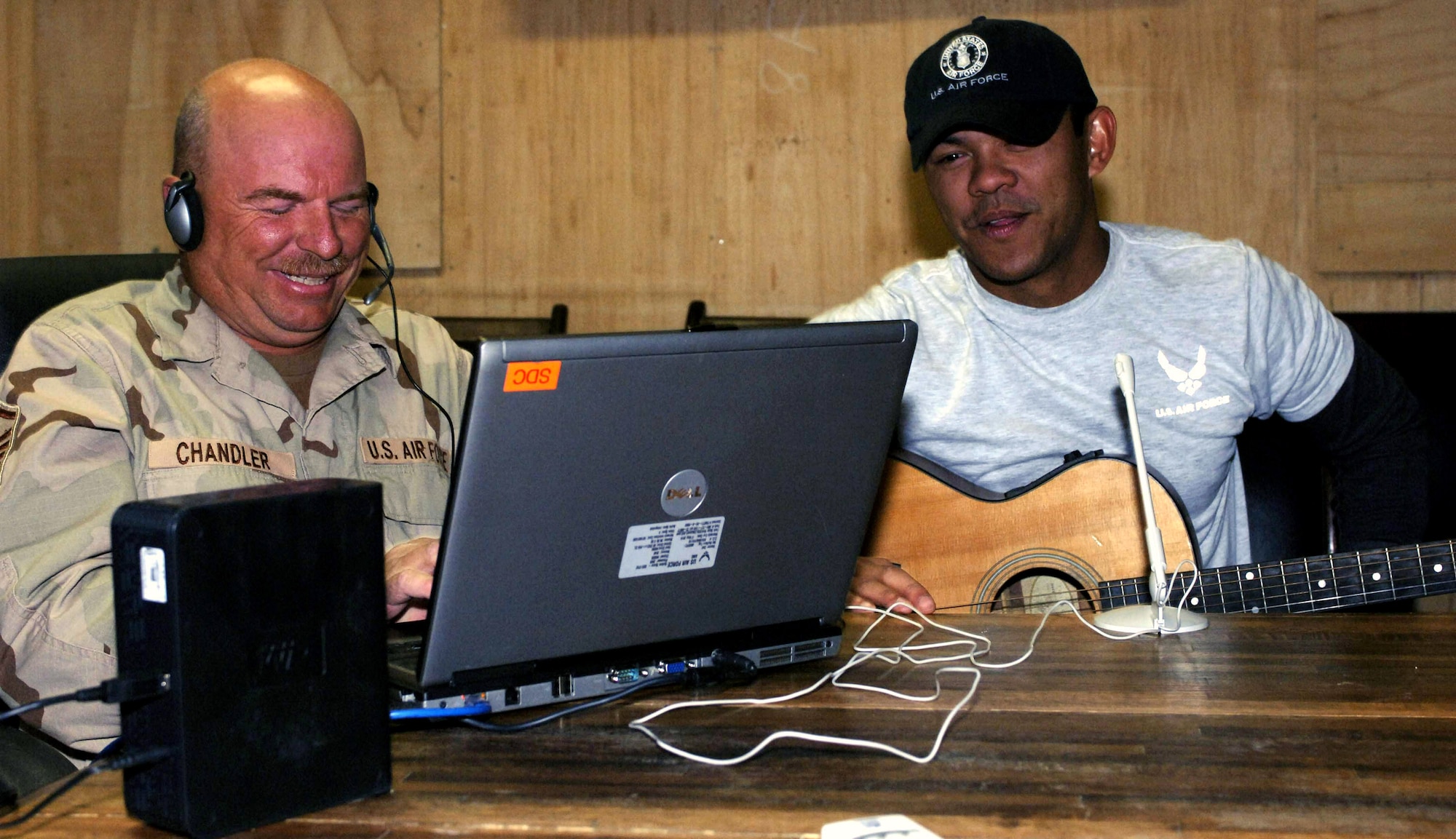 Master Sgt. Tim Chandler (left) of Ashland, Ohio and Staff Sgt. John DeLeon of Redlands, Calif., share a joke during a live broadcast of an Internet radio show at Bagram Air Base, Afghanistan Oct. 28. Sergeant Chandler hosts the show during his free time, and Sergeant DeLeon performs his songs. The program gives Bagram Airmen a vehicle to send long-distance dedications back home to their loved ones. Both Airmen are currently assigned to the 455th Air Expeditionary Wing.  (U.S. Air Force photo/Capt. Michael Meridith) 