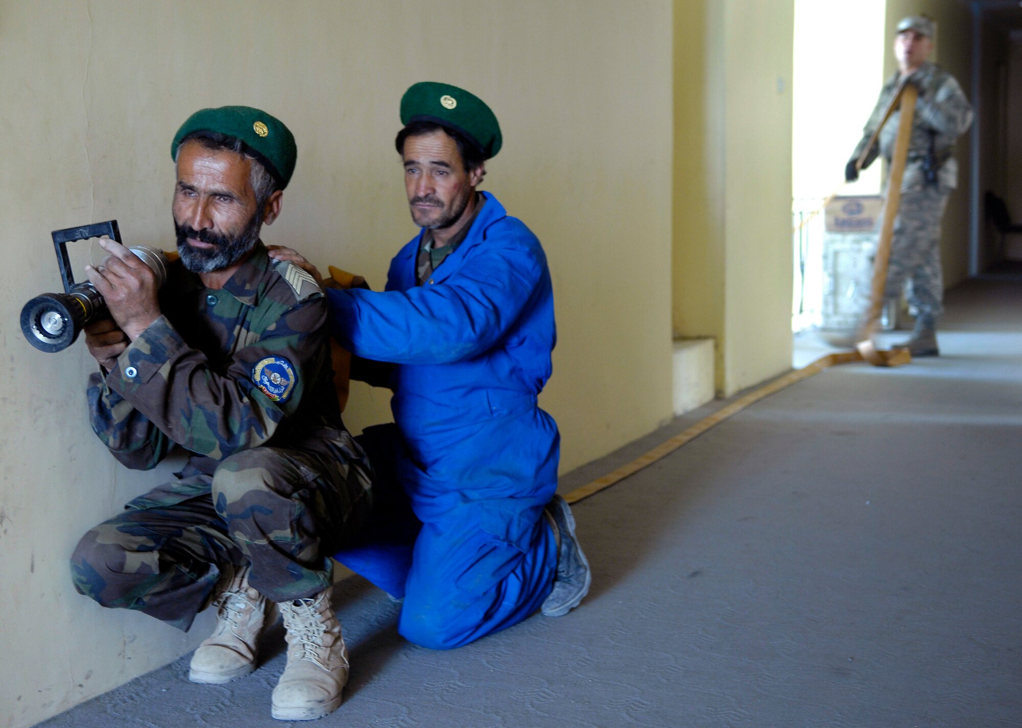 Master Sgt. Tim Rickard looks on as (front) Sgt. Basir and Sgt. Asadullah, Afghan National Army Air Corps firefighters, post in the hallway of a building at Kabul International Airport, Afghanistan, during a training exercise here.  The firefighters are training with Air Force mentors, to build their fire protection capability.  Sgt. Rickard is a firefighter mentor, deployed here from the 36th Civil Engineer Squadron, Andersen Air Force Base, Guam. (U.S. Air Force photo/Staff Sgt. Brian Ferguson)