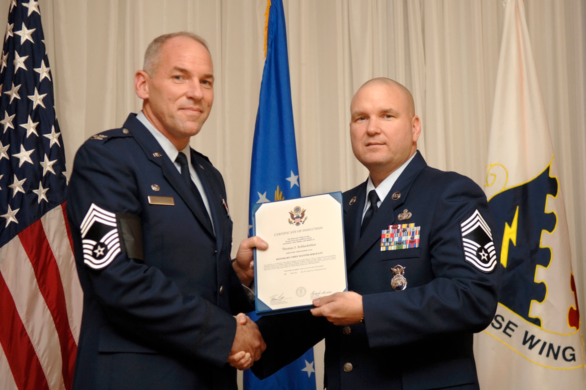HANSCOM AFB, Mass. -- Chief Master Sgt. Tom Purtle, 66th Security Forces Squadron superintendent, presents Col. Tom Schluckebier, 66 ABW commander, with the induction certificate making the colonel an honorary chief Oct. 31. The colonel was bestowed this honor because of his, “unfailing compassion for Hanscom’s enlisted Airmen and their families,” and for being a man of character, revered by chiefs as “a leader among leaders, an Airman among Airmen, and a chief among chiefs,” according to the induction certificate. (U.S. Air Force photo by Jan Abate)