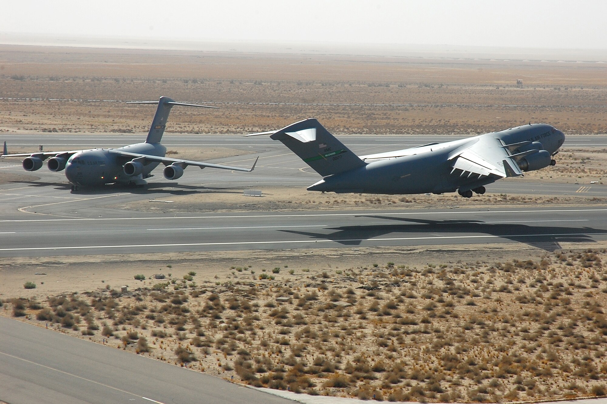 SOUTHWEST ASIA -- A C-17 Globemaster III from McChord AFB, Wash., passes a taxiing C-17 from McGuire AFB, Del., while preparing for take-off Nov. 2 here.  The C-17 has a unique capability of rapid strategic delivery of troops and all types of cargo to main operating bases or directly to forward bases in the deployment area.  (U.S. Air Force photo by Staff Sgt. Tia Schroeder)  
