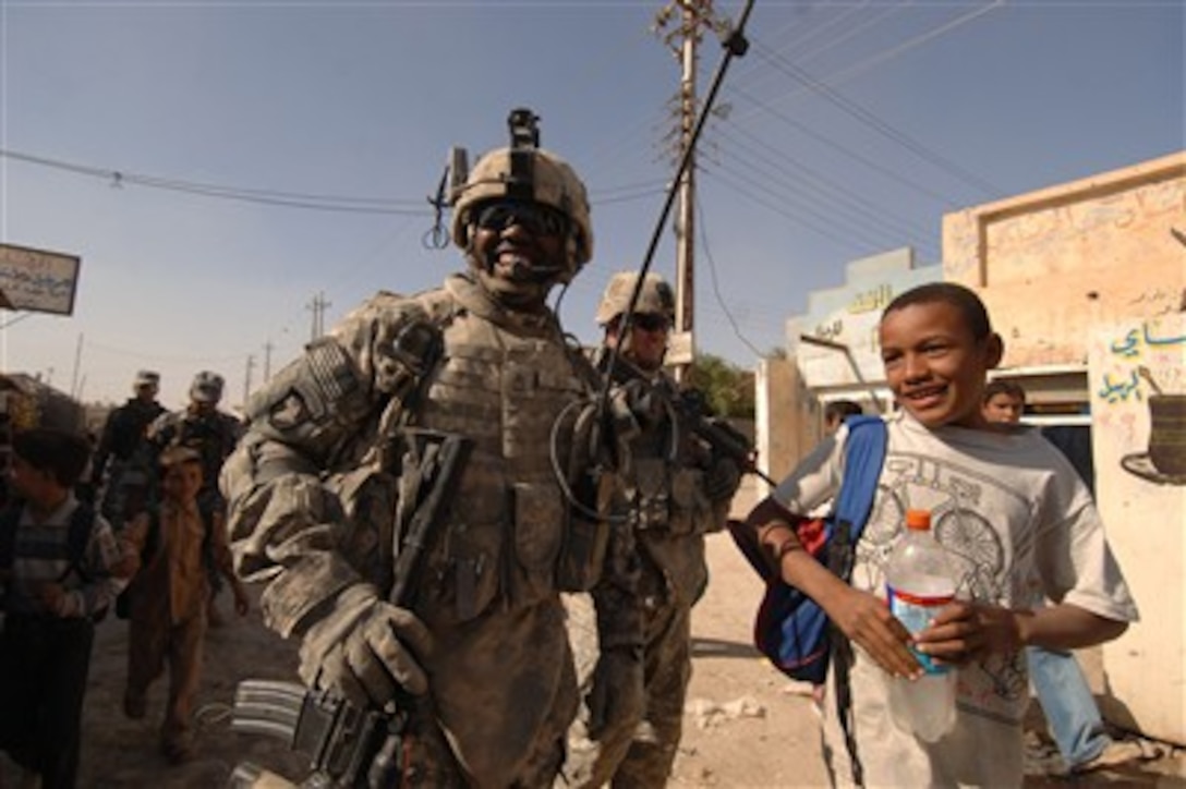U.S. Army Sgt. 1st Class David Bess tells jokes with an Iraqi child during a joint dismounted presence patrol with Iraqi National Police at a market in Narhwan, Iraq, on Nov. 1, 2007.  Bess is from Bravo Troop, 3rd Battalion, 1st Cavalry Regiment, 3rd Heavy Brigade Combat Team, 3rd Infantry Division.  
