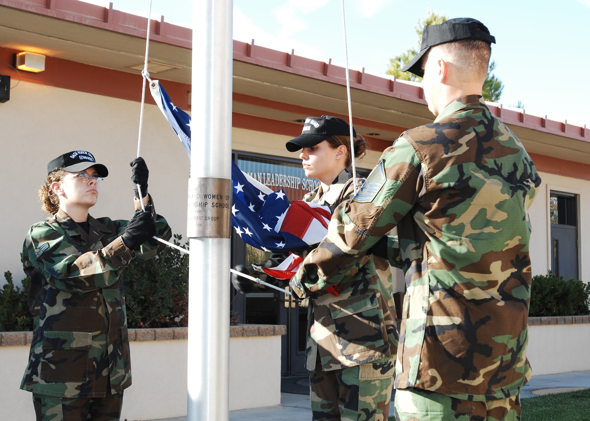 Edwards Blue Eagles Honor Guard members lower the flag during a memorial retreat ceremony for Staff Sgt. Kurt Ellington on Oct. 30 at Airman Leadership School here. Sergeant Ellington, an aircrew survival instructor, was killed in a helicopter crash here Oct. 10, 1991. (Photo by Jim Shryne)