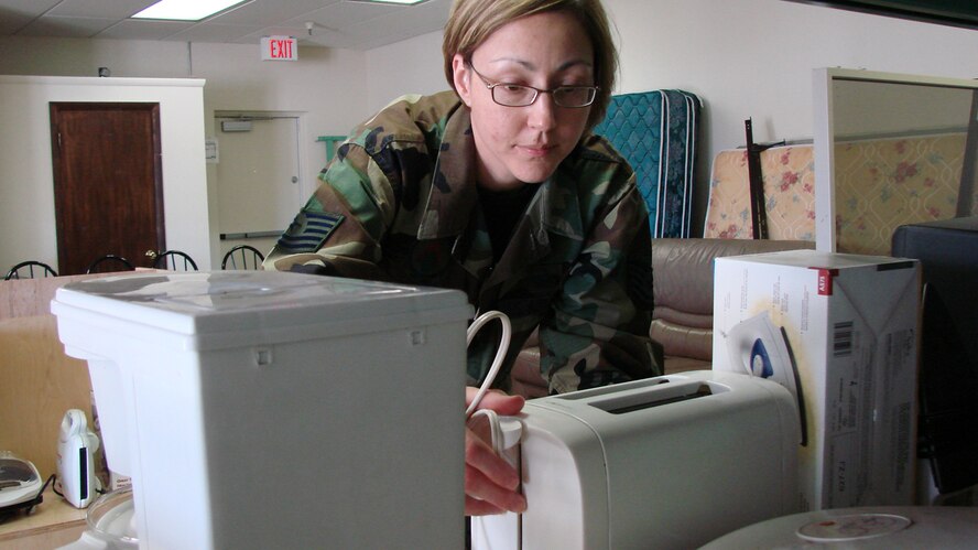Tech. Sgt. Bobbie White, Airman and Family Readiness Center NCO in charge of readiness, places items on the shelf at the new Airman's Attic. The attic provides free items for E-5s and below to alliviate some of the financial hardships some junior enlisted Airmen face. Team Vance members are invited to the ribbon cutting ceremony at 2 p.m., Nov. 20 in Bldg. 415. (U.S. Air Force photo by Tech. Sgt. Mary Davis)