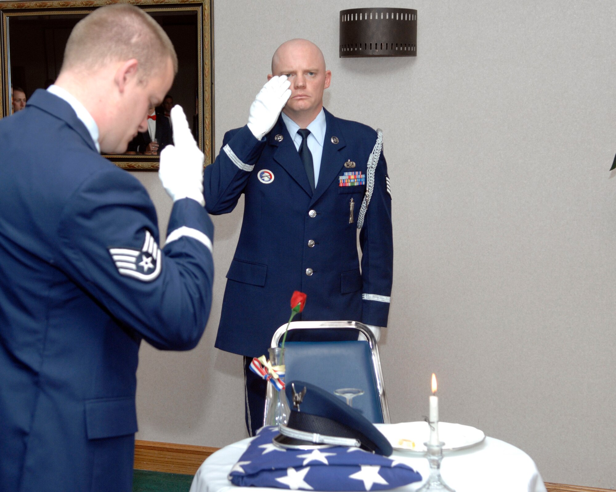 CANNON AIR FORCE BASE, N.M. -- Staff Sgts. David Liddell (left) and Brian Mowry salute a table which is reserved for servicemembers who lost their lives in combat or are missing in action during the 522nd Fighter Squadron's dining out. The dining out celebrated the Fireballs' history before their planned inactivation. (U.S. Air Force photo by Airman 1st Class Erik Cardenas)