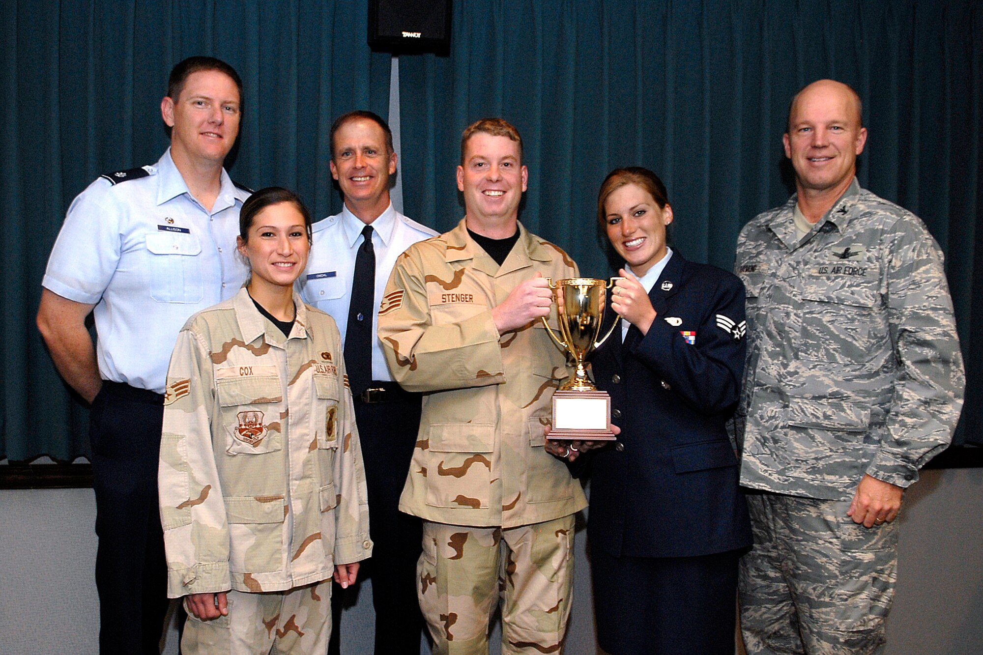 The 21st Security Forces Squadron's investigative section, recipients of the Golden Knight award, hold high the trophy during a special award ceremony Oct. 31. Pictured are (front row, left to right), Senior Airman Jennifer Cox, Staff Sgt. Joseph Stenger, and Senior Airman Christina Burmeister, along with Lt. Col. Thomas Allison, 21st SFS commander, Chief Master Sgt. Tim Omdal, 21st Space Wing command chief, and Col. Jay Raymond, 21st SW commander. The trio investigated a rash of car burglaries on Peterson, leading to the apprehension and subsequent arrest of a suspect. (U.S. Air Force photo by Rob Bussard)