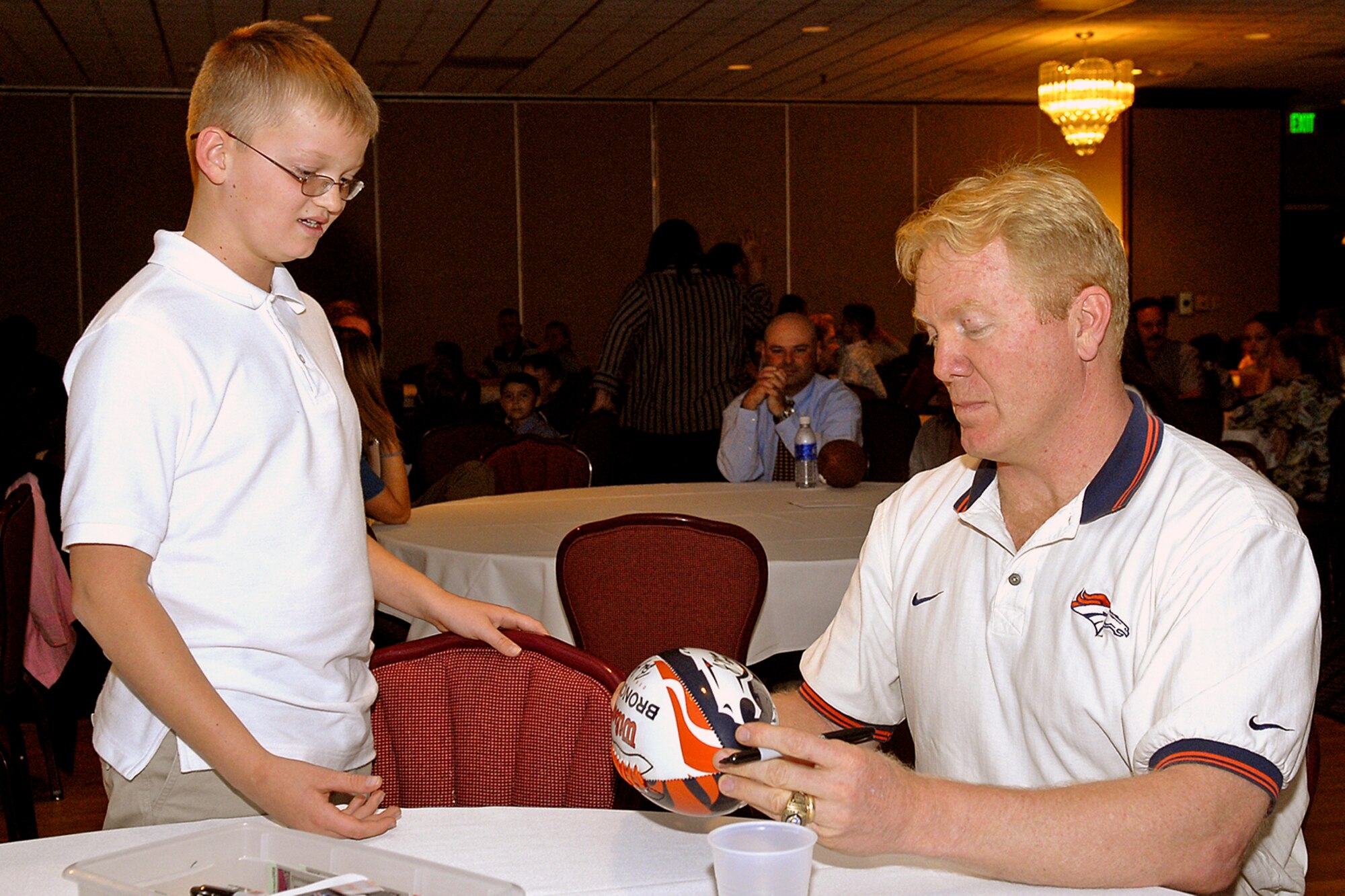 Former Denver Broncos captain and All-Pro Karl Mecklenburg signs a football for Mitchell Flack, son of Tech. Sgt. Harry Metheny and wife Debra. The young Flack is a flag football player and was at The Club Oct. 30 for the 21st Services Squadrons 2007 Flag Football awards ceremony. Mr. Mecklenburg rose from being a college walk-on and a 12th round draft pick to a pro career that included six Pro Bowl and three Super Bowl appearances. He was the guest of honor at the ceremony. (U.S. Air Force photo by Rob Bussard)