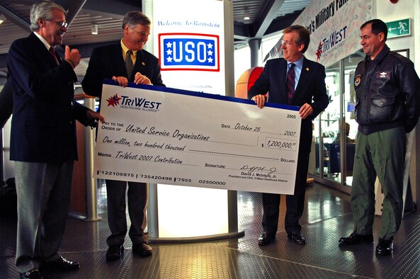 (From left) Bill Moll, United Service Organizations chairman of the board of governors, and Edward A. Powell, USO Jr. president and chief executive officer, accept a donation of $1.2 million from David McIntyre, TriWest Healthcare Alliance president and chief executive officer, with the company of Maj. Gen. Marc Rogers, U.S. Air Forces in Europe vice commander, on Ramstein Oct. 25. About $150,000 goes to the Ramstein’s Passenger Terminal USO for continued upgrades and maintenance. (Photo by Airman 1st Class Marc I. Lane)
