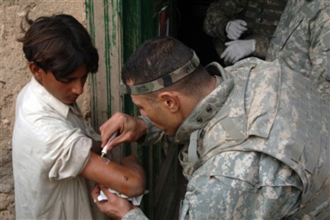 U.S. Army Staff Sgt. Terek Khalil, a medic from Charlie Company, 2nd Battalion, 503rd Parachute Infantry Regiment, treats and bandages an arm injury on a young boy in Chiriac Valley, Afghanistan, on Oct. 24, 2007.  