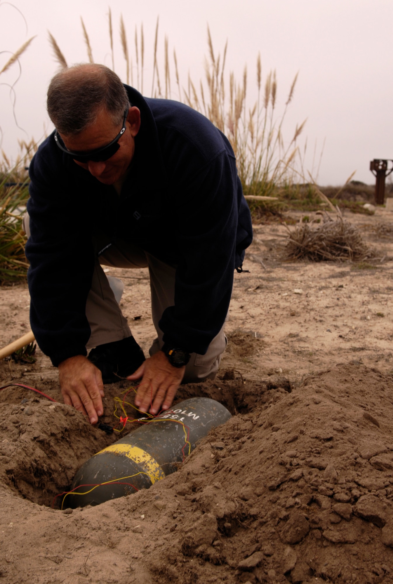 VANDENBERG AIR FORCE BASE, Calif. -- Ron Capra, with the Los Angeles Police Department Bomb Squad, conceals a secondary explosive device with dirt prior the detonation of 500 pounds of explosives used to demolish an ambulance during Federal Bureau of Investigations post-blast investigator training on Nov. 6. Federal, state and local law enforcement officers involved in bomb crime-scene investigations participate in this one-week course which places an emphasis on the identification and collection of fragmented and mutilated bomb components. (U.S. Air Force photo/Airman 1st Class Christian Thomas)
