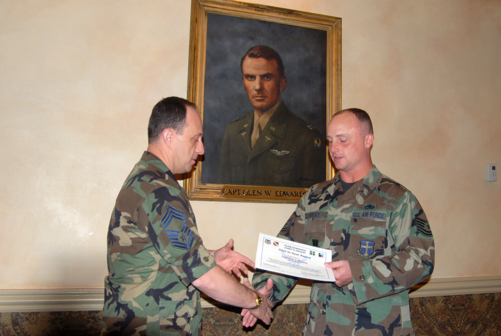 Chief Master Sgt. James Collins (left), 412th Aircraft Maintenance Squadron Joint Strike Fighter maintenance superintendent, congratulates Tech. Sgt. Karl Morsey, Air Force Flight Test Center Museum interim director, for receiving the Chief's Group's Dare to Soar award. The Dare to Soar award is presented to Airmen for outstanding performance. (Photo by Airman 1st Class Mike Young)