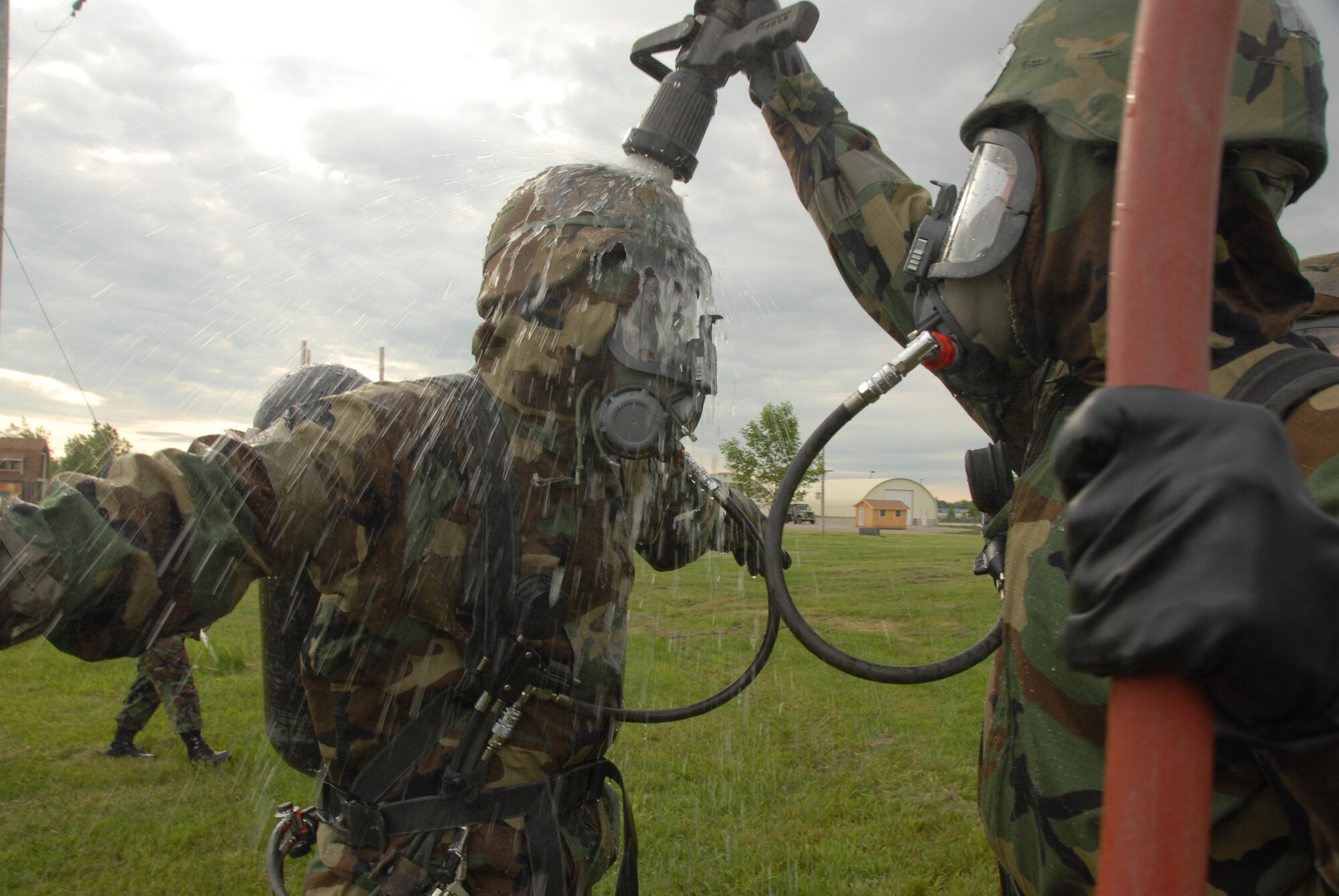 Staff Sgt. Matthew Lasek decontaminates Airman 1st Class Lyndsey Barclay, both of the 138th Civil Engineer Squadron, after completing the dike, dam, divert and retain practical portion of the HAZMAT operations level certification course at the North Dakota Air National Guard Readiness Training Site June 6. (U.S. Air Force photo by Senior Master Sgt. David H. Lipp)