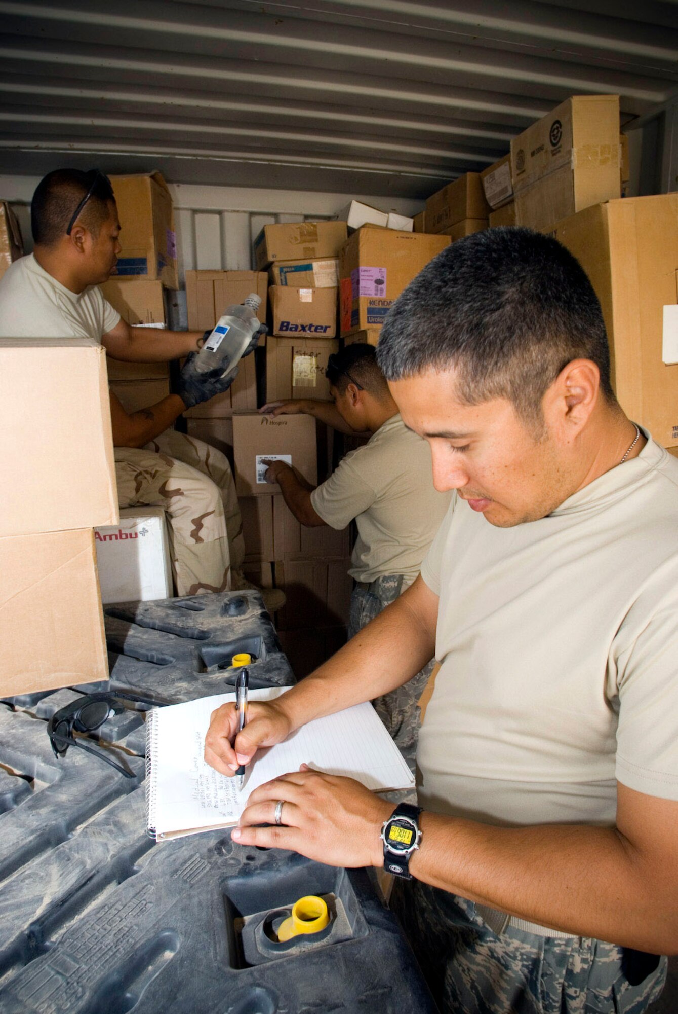 Tech. Sgt. Richard Carditl (front) records the product name, quantity and national stock number of the items read off to him by Staff Sgt. Benito Isla (left) and Staff Sgt. Dendouang Moungsiharat inside a container express Oct. 19 at Camp Corregidor, Iraq. Serviceable assets recovered from the conex are inventoried and redistributed to Army units throughout Iraq. Airmen of various career fields augment the Army in nontraditional "in-lieu-of" taskings for up to a year. Sergeant Carditl is deployed from Shriever Air Force Base, Colo., Sergeant Benito Isla from Edwards AFB, Calif., and Sergeant Moungsiharat from Peterson AFB, Colo. (U.S. Air Force photo/Master Sgt. John Nimmo Sr.) 
