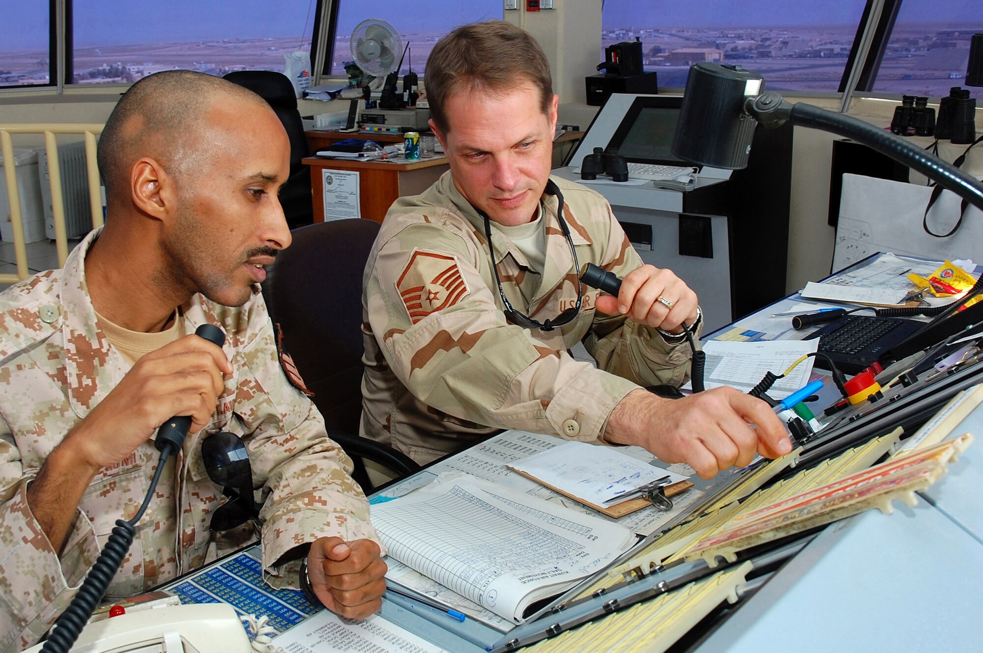 Sgt. Abdullah Al. Ajmi and Master Sgt. James Armstrong look over flight progress strips used to track aircraft information during takeoffs and landings Nov. 2 in Southwest Asia. Sergeant Armstrong, the 386th Operations Group air traffic controller NCO in charge, is deployed from Royal Air Force Mildenhall, England. Sergeant Ajmi is a host nation air traffic controller. (U.S. Air Force photo/Staff Sgt. Tia Schroeder) 
