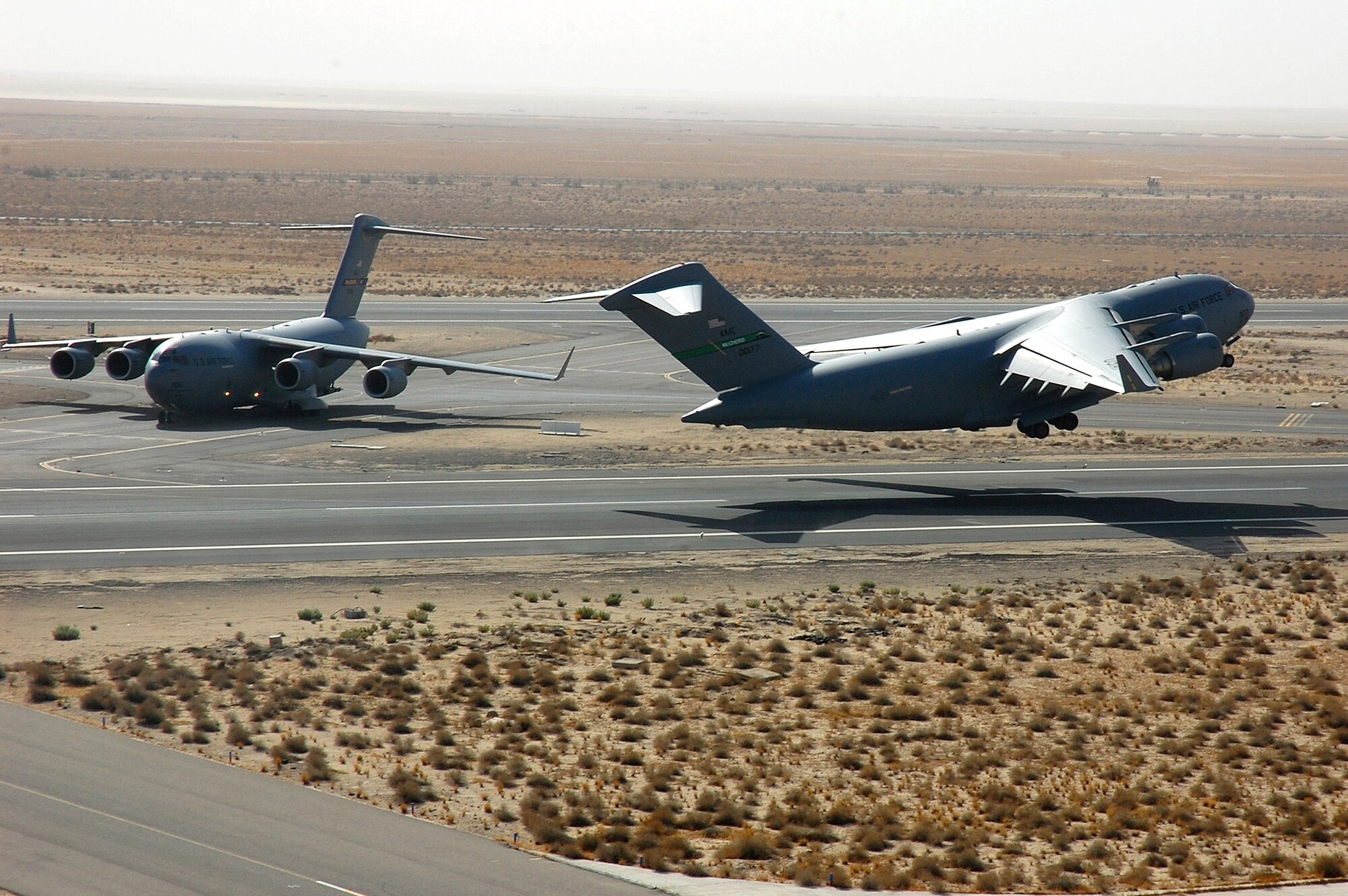 A C-17 Globemaster III from McChord AFB, Wash., takes off while passes a taxiing C-17 Nov. 2 in Southwest Asia. The C-17 rapidly delivers troops and all types of cargo to main operating bases or directly to forward bases in the deployment area. (U.S. Air Force photo/Staff Sgt. Tia Schroeder) 
