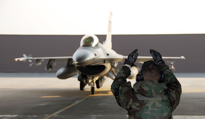 OSAN AIR BASE, Republic of Korea -- Senior Airman Elias Maldonado, F-16 Crew chief, directs an F-16 into the hangar for maintenance. During a peninsula wide exercise here. The exercise Beverly Bulldog 08-01 scenarios test Team Osan's ability to defend the base and conduct daily operations in a combat environment. (U.S. Air Force Photo by Staff Sgt Ronnie Hill) (Released) 