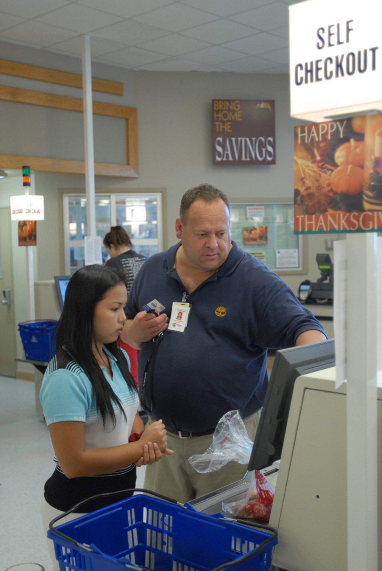 Phil Petrazio (right), IBM Trainer with DECA, helps a customer use one of the new self checkout lanes at Kadena’s commissary Nov. 8. The commissary recently installed four self checkout lanes for customers to get in and out quickly. 
(U.S. Air Force/Airman 1st Class Kasey Zickmund)