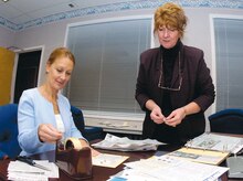 Paula McKinley, left, aids Patricia Botkins, Andrews Airman and Family Readiness flight chief with archiving news clippings from past Capital Flyer newspapers on Nov. 5, which illustrate the center's publicizing of family-oriented events. Paula McKinley is the wife of Chief Master Sergeant of the Air Force Rodney J. McKinley.(US Air Force/Bobby Jones)