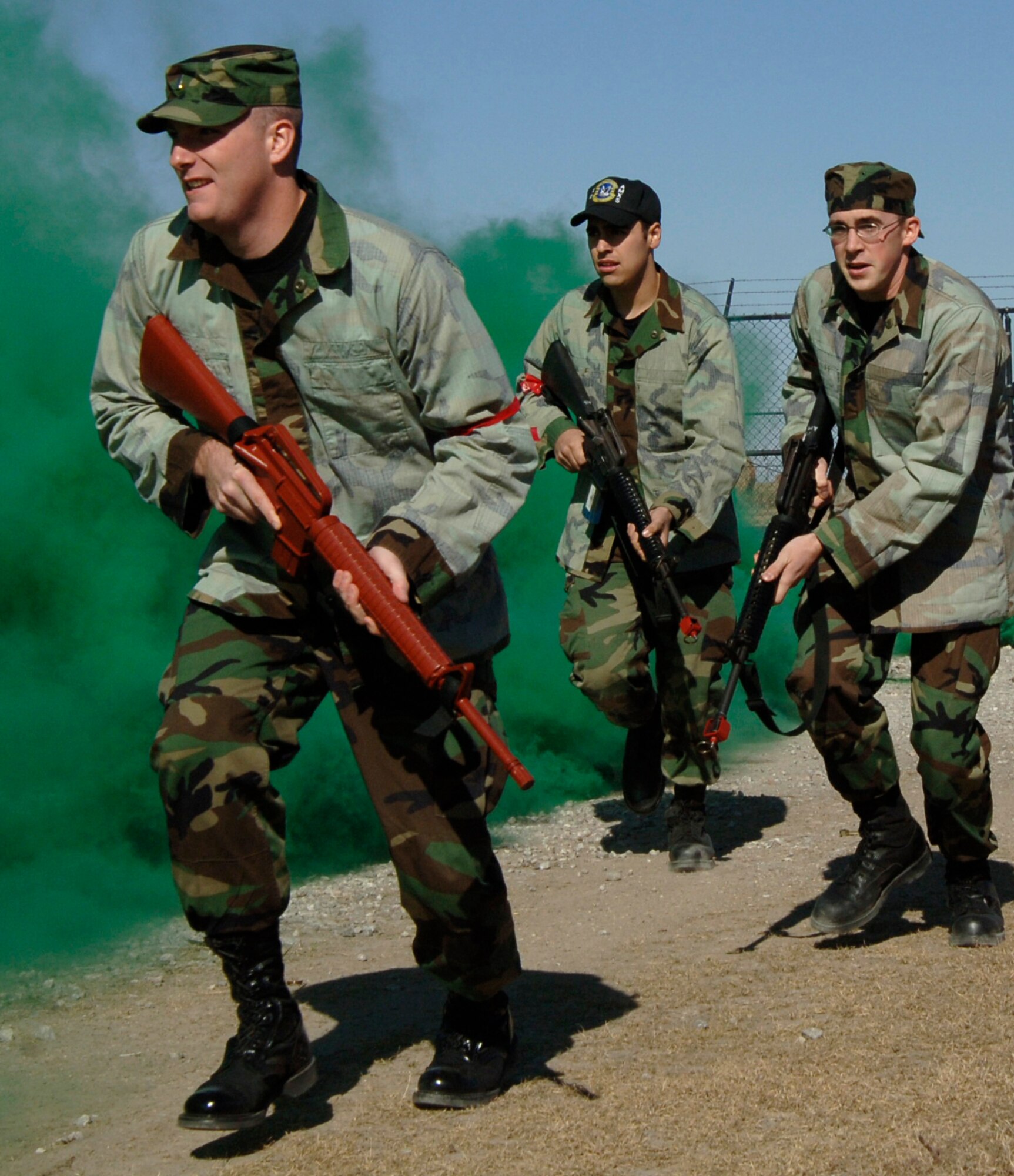 MCCONNELL AIR FORCE BASE, Kan. -- 2nd Lt. Timothy Bexten, left, 349th Air Refueling Squadron, Senior Airman Brandon Mcanally, right, 349th Air Refueling Squadron and Airman Steven Garcia, 22nd Aircraft Maintenance Squadron are running to the Alert Facility Bldg. 978 while green smoke covers their approach during the Injured Walker exercise Nov. 06. ATSO exercise challenges military personnel’s capability to respond.  (Photo by Airman 1st Class Roy Lynch) 