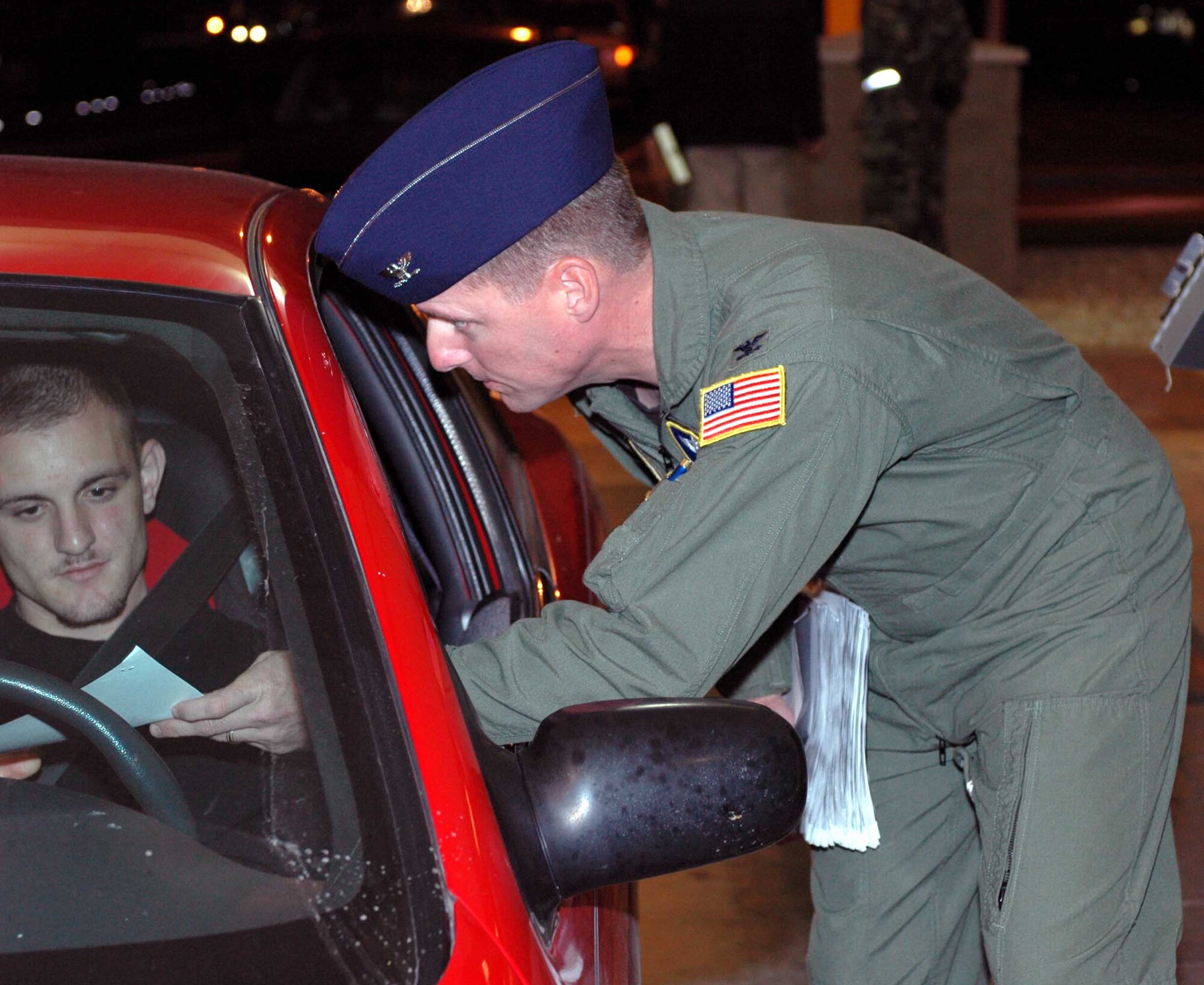 Col. John Wood, 60th Operations Group deputy commander, hands a letter to a base patron during Operation Nighthawk. The letter, an order by the base commander, instructed all military members to report for a urinalysis test. Operation Nighthawk is a Team Travis leadership program used to provide a Health, Morale, and Welfare check with feedback to leadership on the status and activities of the members assigned to the installation, their family members and visitors to the installation. (U.S. Air Force photo/Capt. Vanessa Hillman)