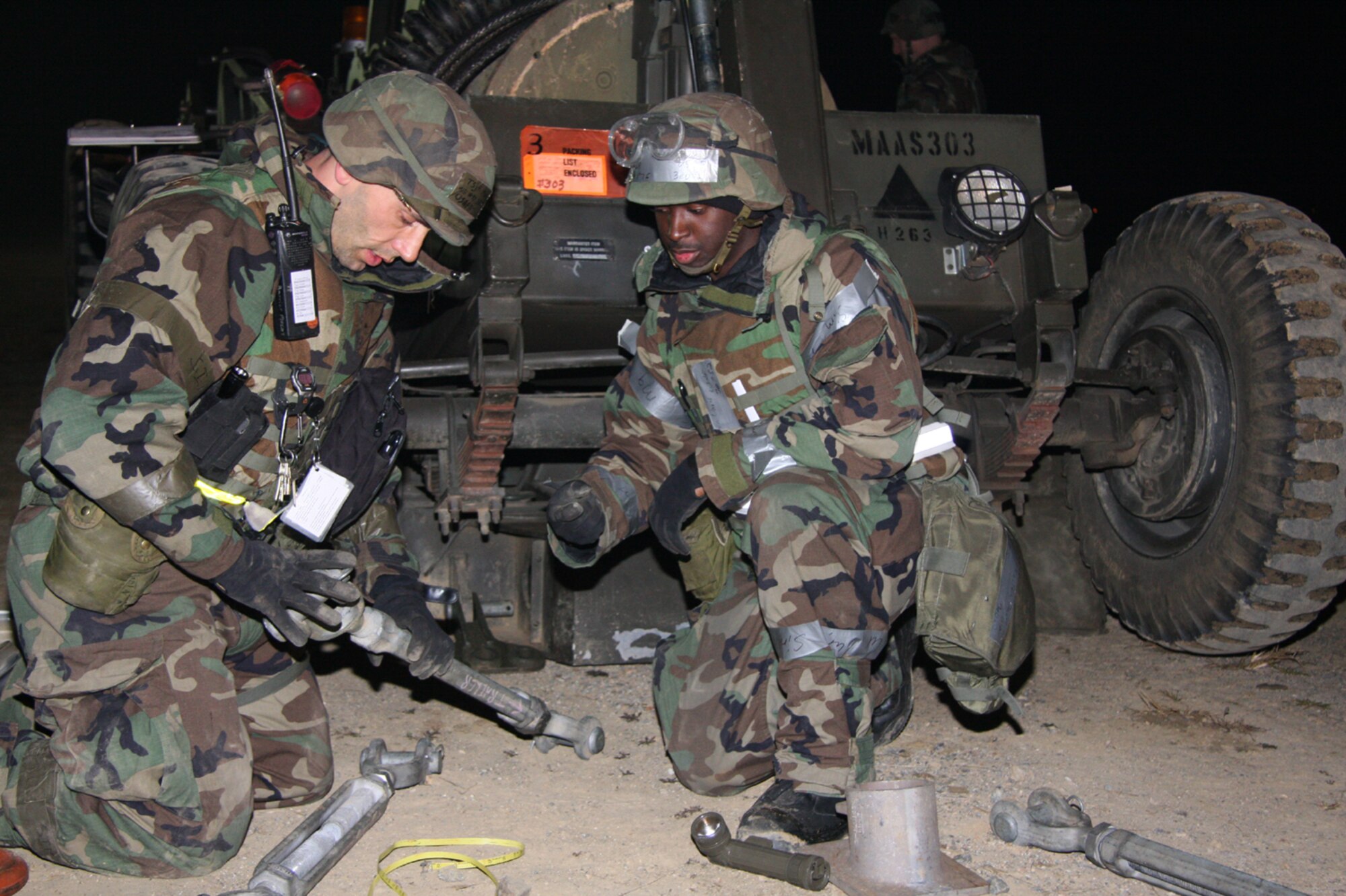 OSAN AIR BASE, Republic of Korea --  Senior Airman Karlton Davis and Tech. Sgt. Jason Munn, both with the 51st Civil Engineer Squadron, adjust the length of a soil anchoring point turnbuckle on the Mobile Aircarft Arresting System here Nov. 7. Beverly Bulldog 08-01, a week-long peninsula-wide exercise, tests the readiness of and provides chemical warfare training to military members assigned to the region. (Photo by Master Sgt. Benjamin Huseman)