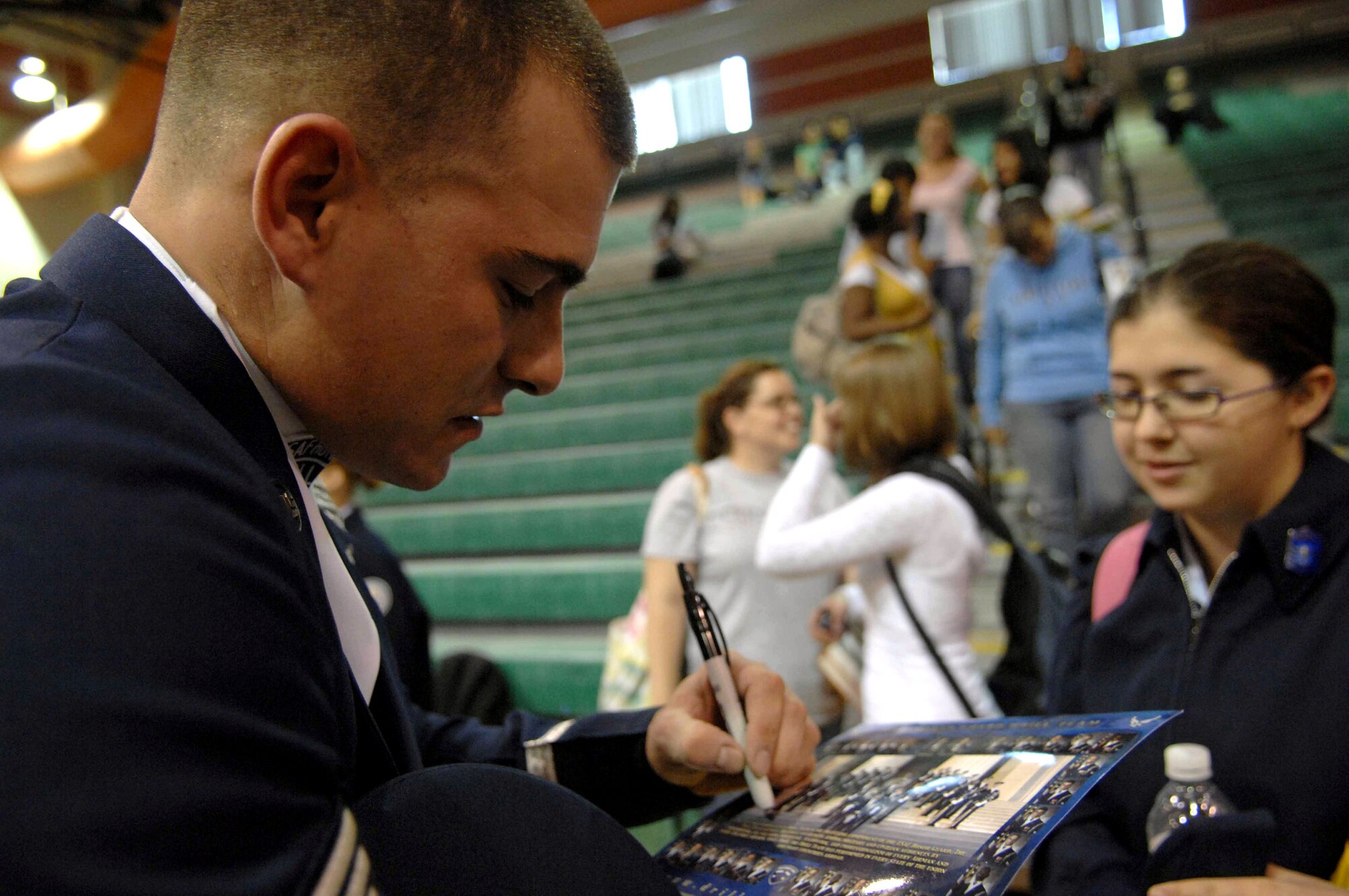 Senior Airman Adam Clonick autographs a souvenir for a Air Force Junior ROTC cadet after the Air Force Honor Guard drill team performance at the Palo Verde High School gym Nov. 6 in Las Vegas. The Air Force Honor Guard drill team is in Las Vegas for 14 performances throughout the military and civilian community and will perform during the Air Force 60th Anniversary Air Show and opening for Tops In Blue. Airman Clonick is an Air Force Honor Guard drill team member and operations coordinator.  (U.S. Air Force photo/Senior Airman Larry E. Reid Jr.)