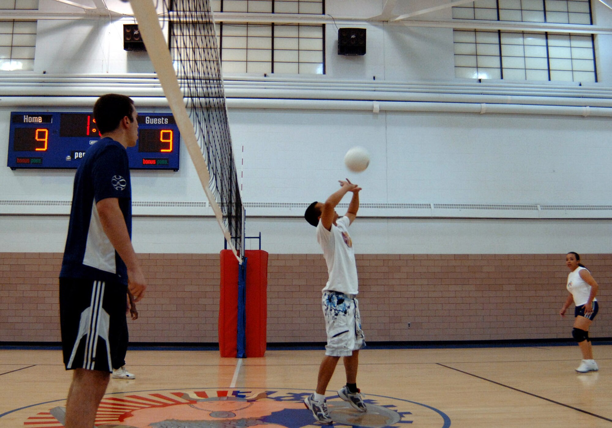 Ross Carreon, 319th Communications Squadron , sets the ball as defense towards the net against the receiving team, the Tater Skins (Michael Anthony, 319th Force Support Squadron, Rhonda Olheiser, 319 FSS; Diane Henderson, 319 FSS; Donald Johnson, 319 FSS) during a volleyball tournament Oct. 30. (U.S. Air Force photo/Senior Airman SerMae Lampkin)