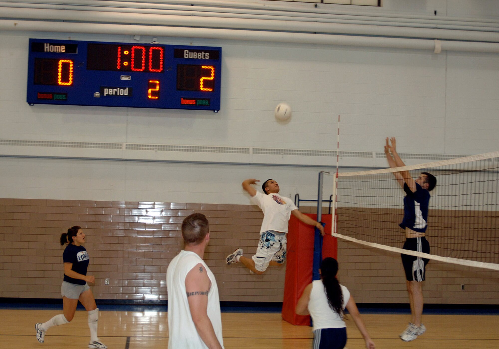 Ross Carreon, 319th Communications Squadron, leaps in the air, poised for a powerful attempt to successfully whack the ball over the net against Donald Johnson's, 319th Force Support Squadron, efforts to guard and block on the receiving end during a volleyball tournament Oct. 30. (U.S. Air Force photo/Senior Airman SerMae Lampkin)