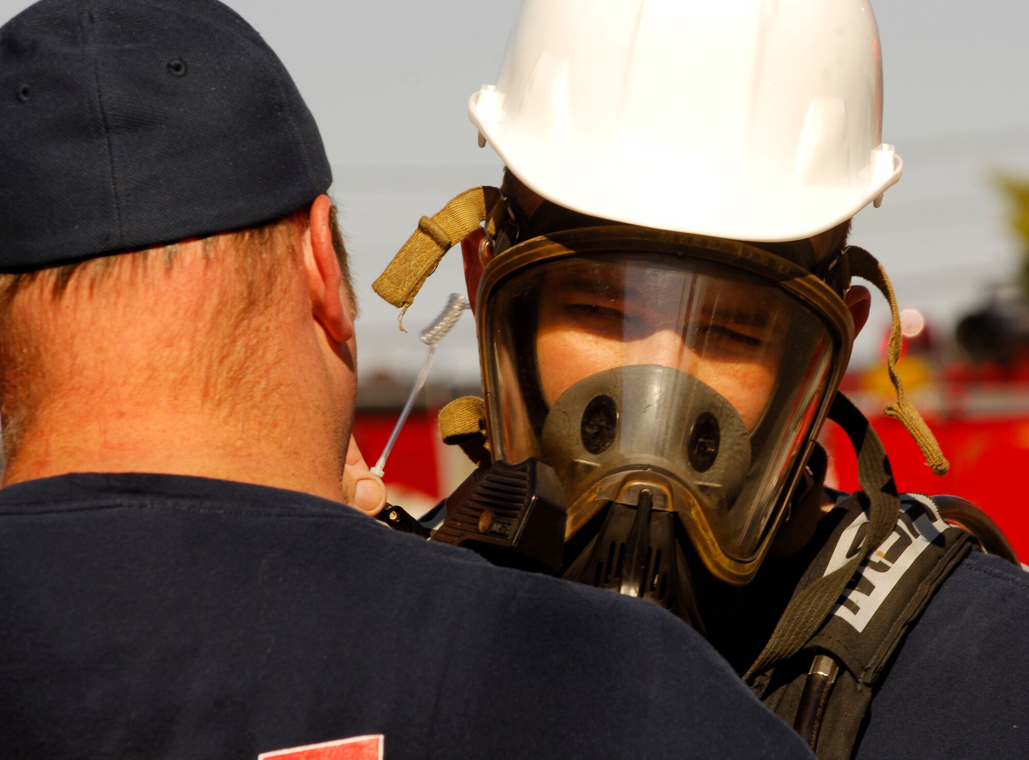 LANGLEY AFB, Va. -- Fred Schmid (left), a medic fire fighter with the Hampton Fire Department Hazmat Team, assists Chris Marshall (right) with his communications module during a Major Accident Response Exercise Nov. 7. The MARE was designed to test reaction and response times as well as the recovery process of Langley and local major accident response personnel if an environmental mishap were to take place on or near the installation. (U.S. Air Force Photo/Staff Sgt Samuel Rogers)