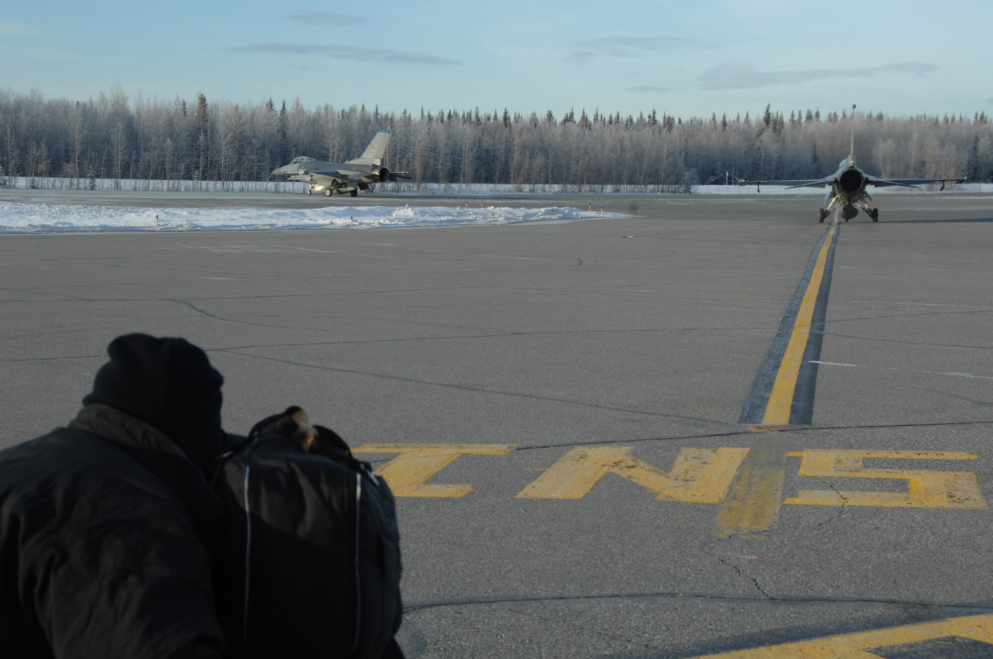 EIELSON AIR FORCE BASE, Alaska -- Graham Steele, director of photography for the Discovery Channel's show Future Weapons, documents F-16 Fighting Falcons taxi down the Eielson AFB flightline Nov. 7, 2007.  The Future Weapons crew is visiting Eielson to document arctic survival training conducted by Det.1, 66th Training Squadron, otherwise known as "Cool School," and the Joint Precision Airdrop System being used under arctic conditions. (U.S. Air Force photo by Airman 1st Class Christopher Griffin)(Released)