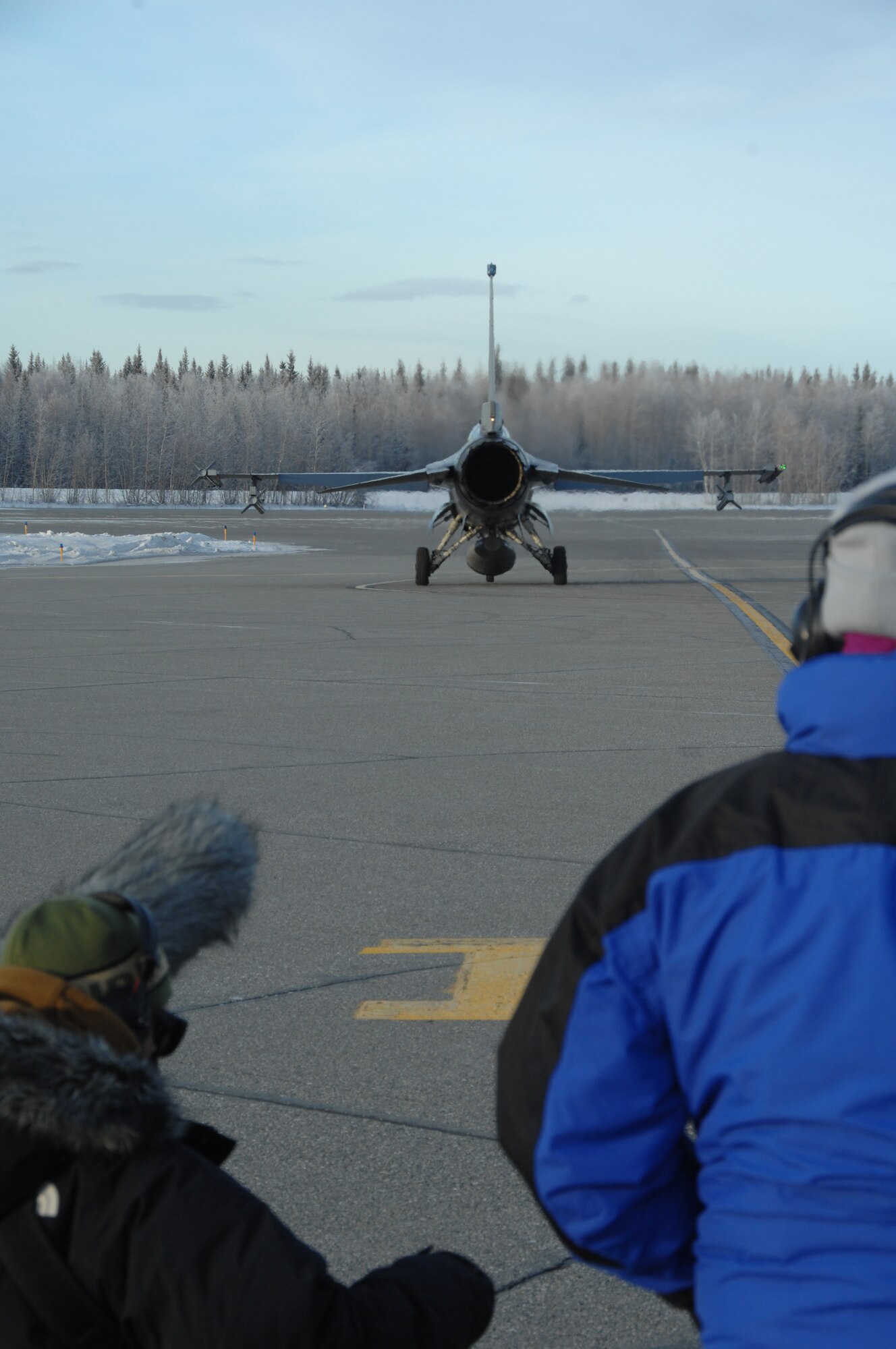 EIELSON AIR FORCE BASE, Alaska -- Jason Kuppig, sound operator, Dr. Louise V. Say, director, watch as an F-16 Fighting Falcon taxis down the Eielson flightline Nov. 7, 2007. The Future Weapons crew is visiting Eielson to document arctic survival training conducted by Det.1, 66th Training Squadron, otherwise known as "Cool School," and the Joint Precision Airdrop System being used under arctic conditions. (U.S. Air Force photo by Airman 1st Class Christopher Griffin)