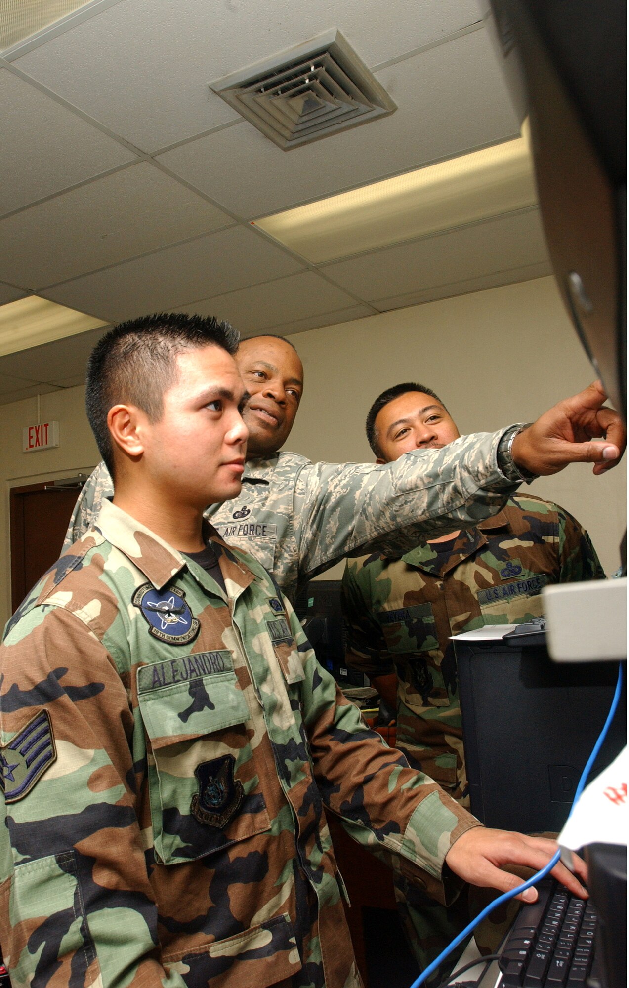 Master Sgt. Rickey Bryant (center), Senior Master Sgt. Vincent DeVera (right) and Staff Sgt Matthew Alejandro troubleshoot a component of the Andersen Air Force Base, Guam communications network. (Air Force photo/Senior Airman Brian Kimball)