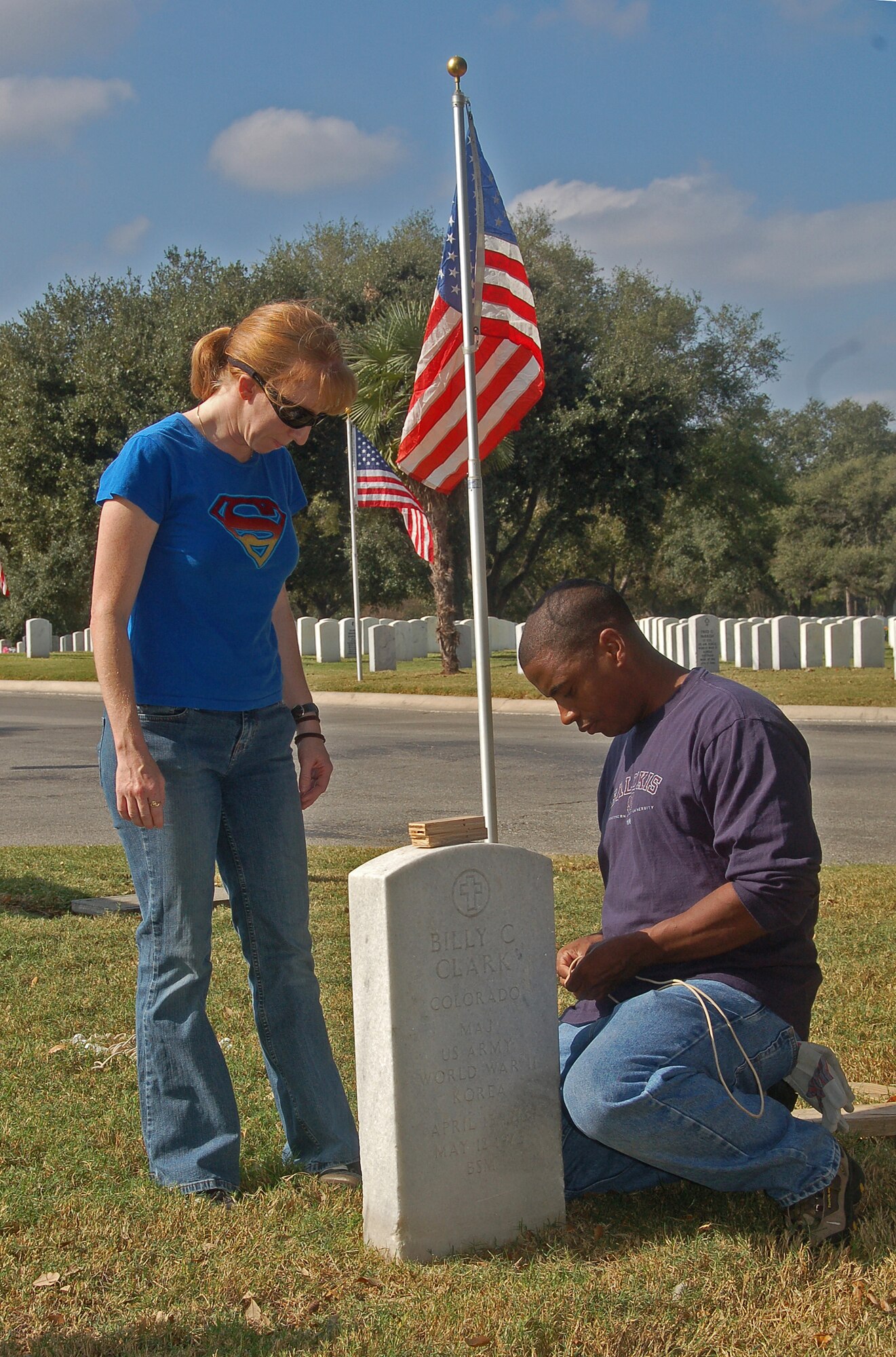 Capt. Shannon Collins and Master Sgt. Reiko Meeks prepare to realign a grave marker Nov. 9 at the Fort Sam Houston National Cemetery in San Antonio. Airmen volunteered to reset the grave markers to honor fallen heroes for Veterans Day. Both are assigned to the Air Force News Agency. (U.S. Air Force photo/Master Sgt. Lee Roberts)