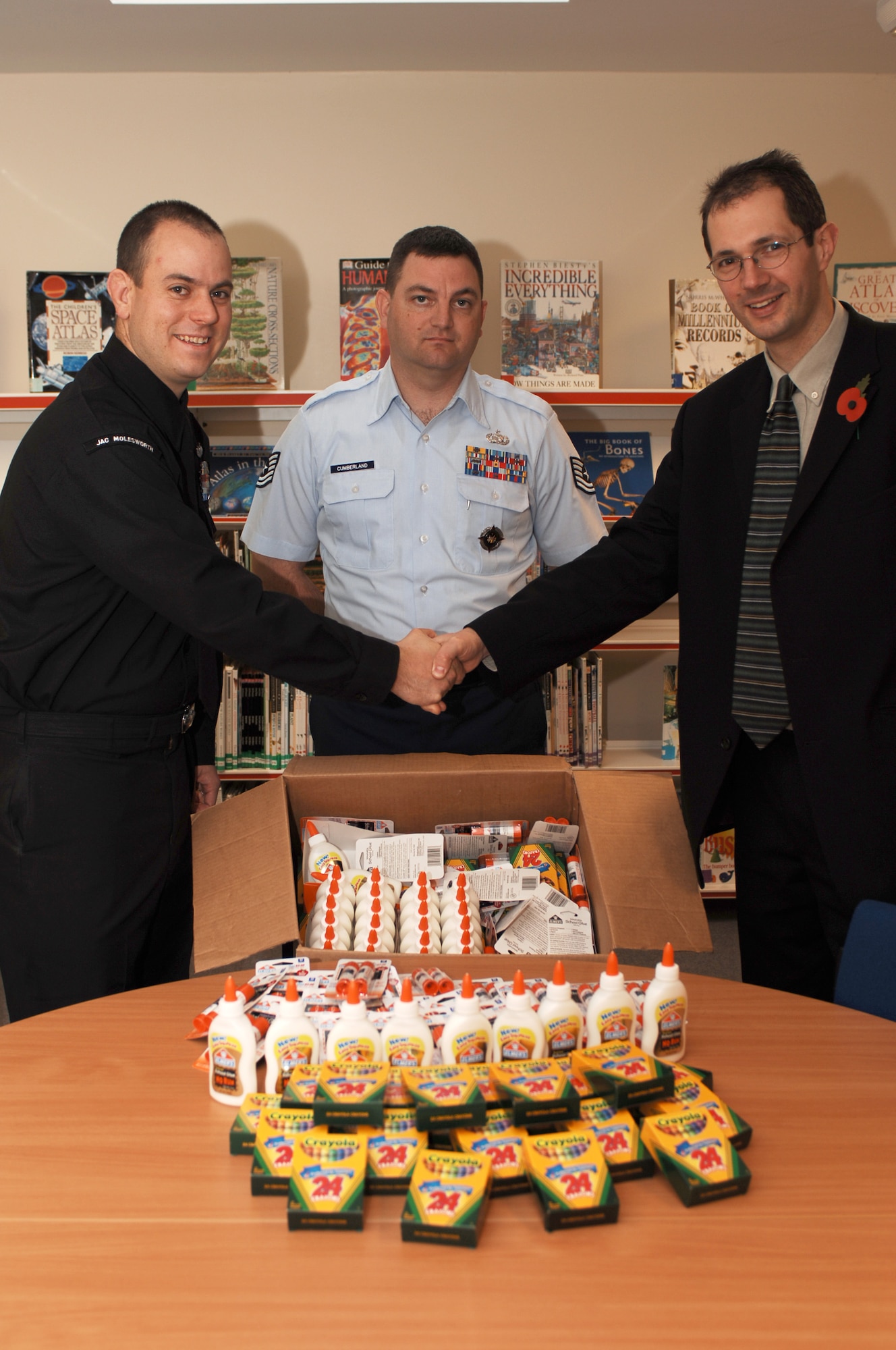 Brington Church of England Primary School Headmaster Mr. Peter Allen thanks U.S. EUCOM Joint Analysis Center Navy Petty Officer 1st Class Jason Snellings as Air Force Tech Sgt Noel Cumberland of the Regional Support Center looks on.  Along with JAC photographer Air Force Staff Sgt. Jocelyn Rich, the members of the JAC E-6 Association presented school supplies to the local British school.  (U.S. Air Force Photo by Staff Sgt. Jocelyn L. Rich)