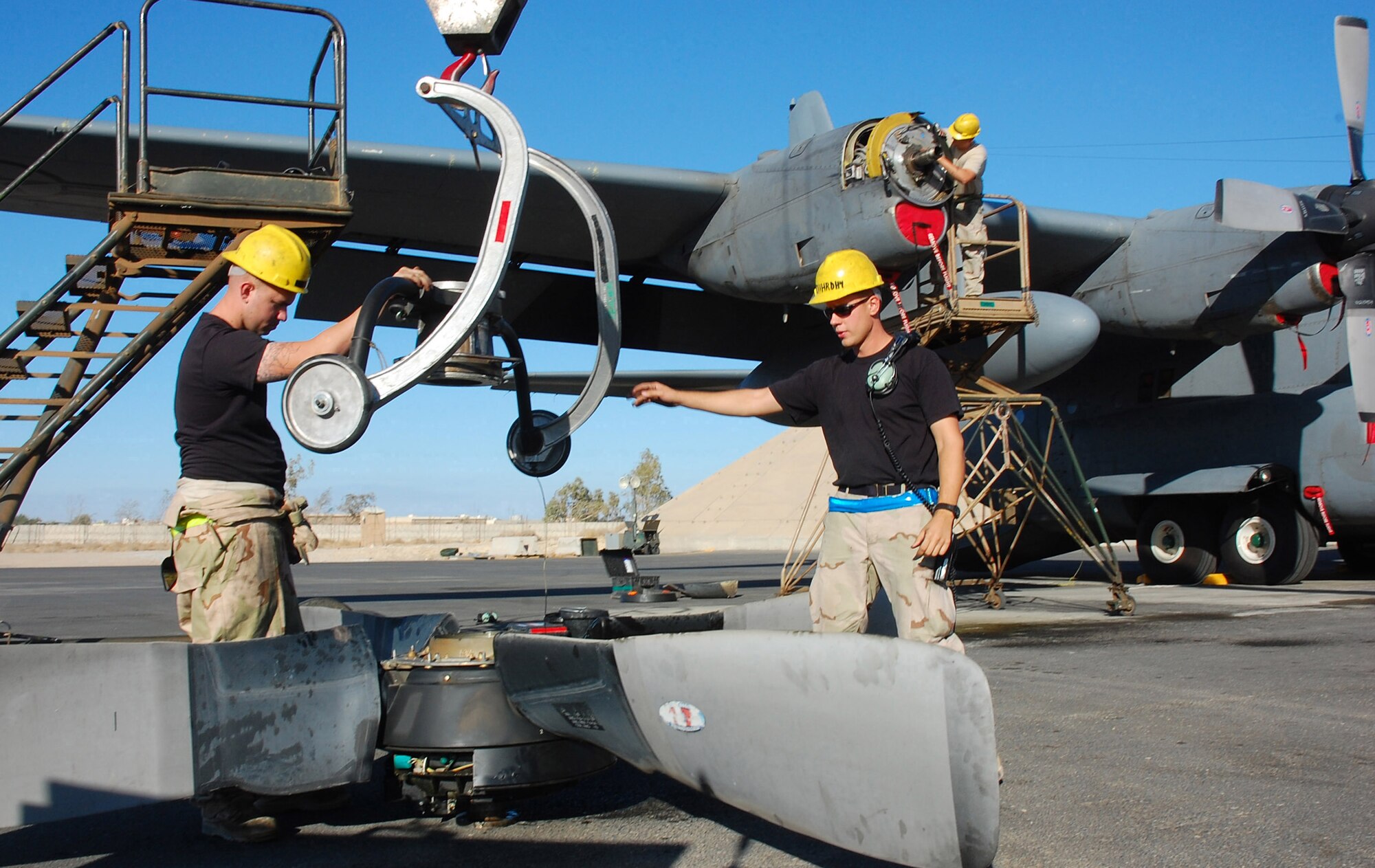 SOUTHWEST ASIA -- Airman 1st Class Joshua Kuzma (left) and Staff Sgt. Nathan Dickey (middle), guide a crane handle to lift up a C-130 Hercules propeller while Staff Sgt. Paul Ratliff removes packings from a prop shaft Nov. 7 here.  The propeller was replaced due to a hydraulic leak in the blade pump housing.  All of the Airmen are 386th Expeditionary Aircraft Maintenance Squadron aerospace propulsion specialists. Sergeant Dickey is deployed from Pope AFB, N.C., Sergeant Ratliff is deployed from Ramstein AB, Germany, and Airman Kuzma is deployed from Yakota AB, Japan.  (U.S. Air Force photo by Staff Sgt. Tia Schroeder)