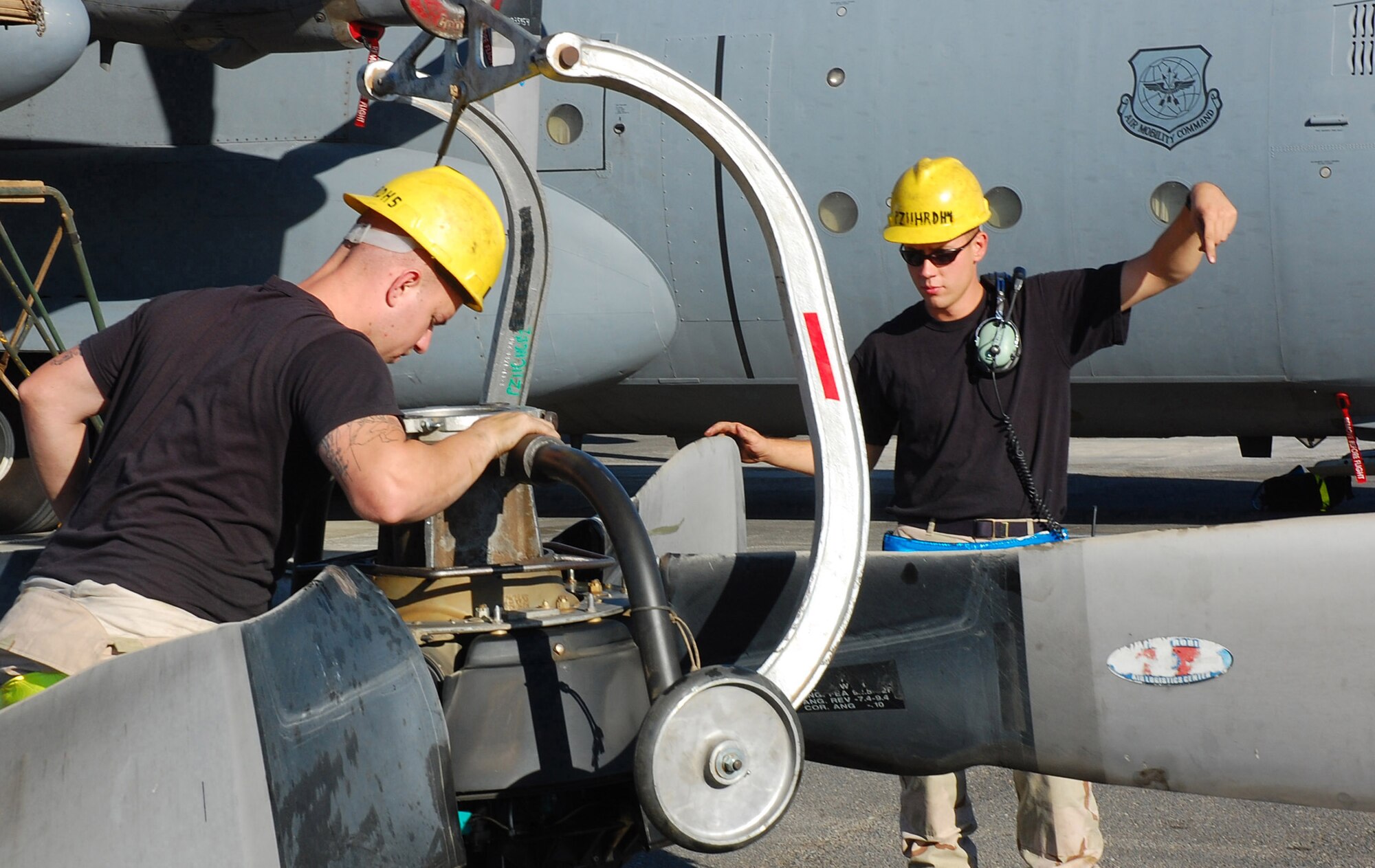 SOUTHWEST ASIA -- Airman 1st Class Joshua Kuzma (left) and Nathan Dickey (right), 386th Expeditionary Aircraft Maintenance Squadron aerospace propulsion specialists, guide a crane handle to lift up a C-130 Hercules propeller Nov. 7 here.  The propeller was replaced due to a hydraulic leak in the blade pump housing.  Sergeant Dickey is deployed from Pope AFB, N.C., and Airman Kuzma is deployed Yakota AB, Japan.  (U.S. Air Force photo by Staff Sgt. Tia Schroeder)