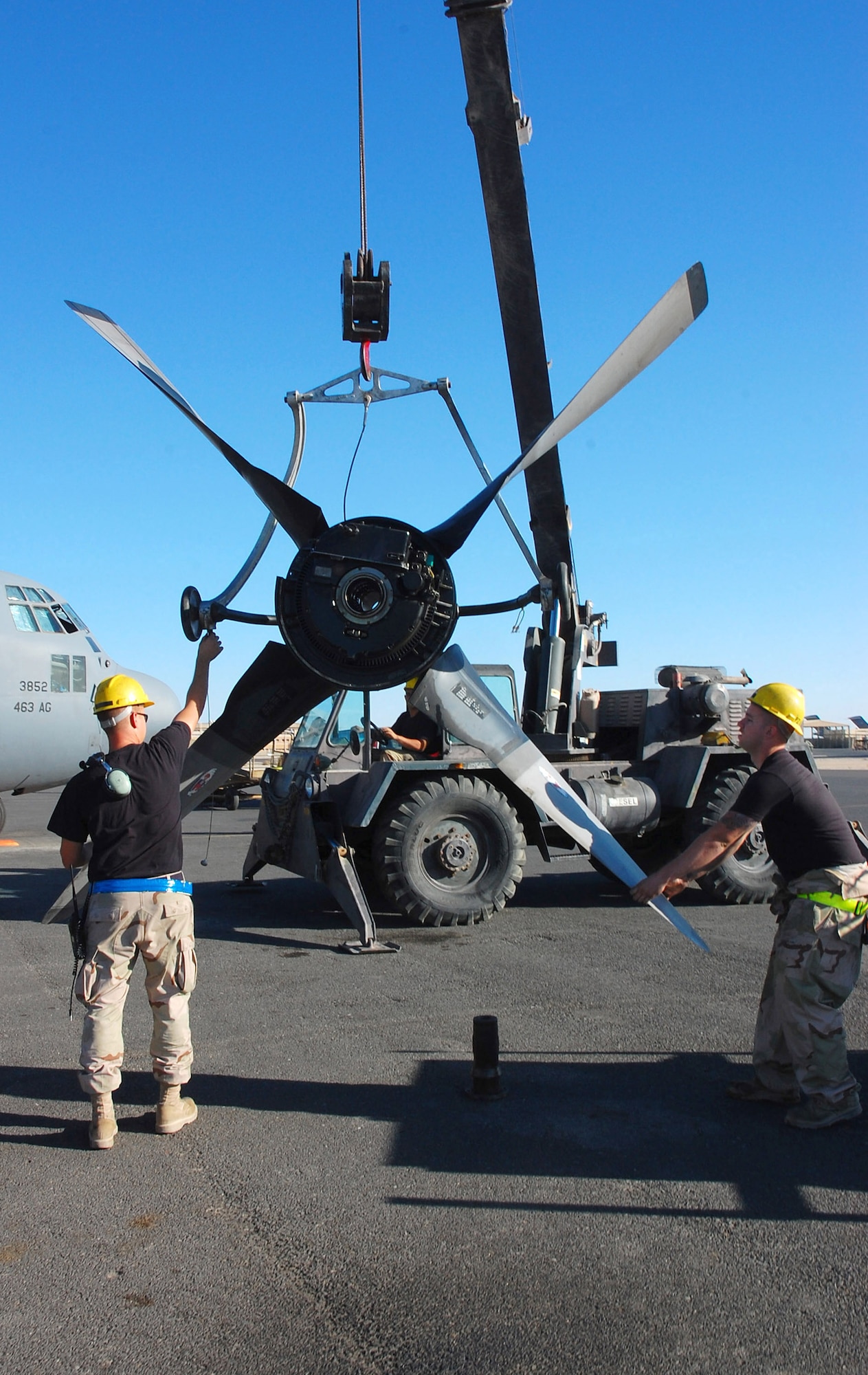 SOUTHWEST ASIA -- Airman 1st Class Joshua Kuzma (left) and Nathan Dickey (right), 386th Expeditionary Aircraft Maintenance Squadron aerospace propulsion specialists, guide a crane handle to lift up a C-130 Hercules propeller Nov. 7 here.  The propeller was replaced due to a hydraulic leak in the blade pump housing.  Sergeant Dickey is deployed from Pope AFB, N.C., and Airman Kuzma is deployed Yakota AB, Japan.  (U.S. Air Force photo by Staff Sgt. Tia Schroeder)