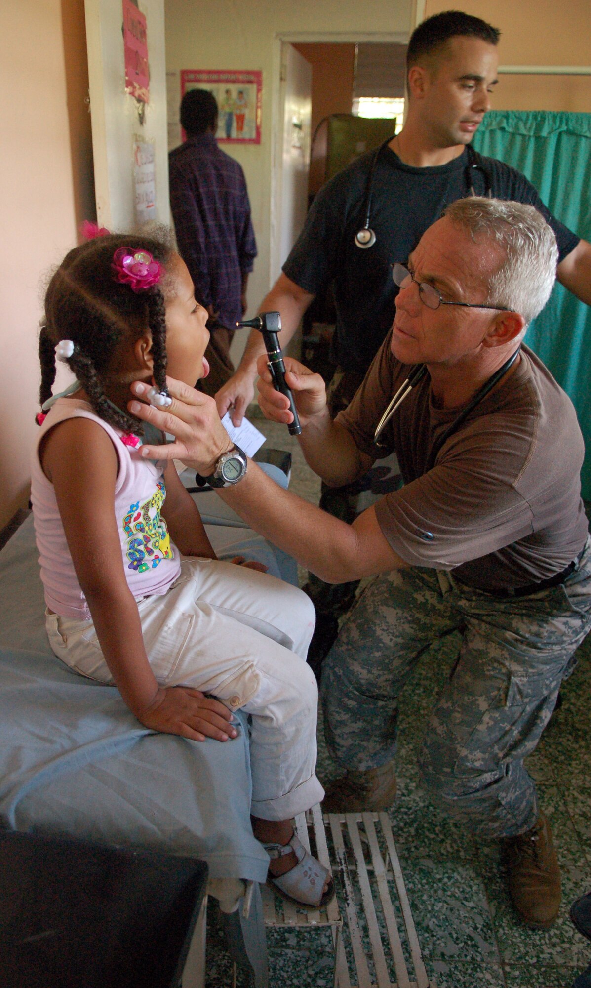 PAYA, Dominican Republic -- Army Lt. Col. (Dr.) Michael Hoilien, assisted by Air Force 1st Lt. Damian Garza, examines the throat of a young Dominican girl at a clinic set up by U.S. servicemembers from Joint Task Force-Bravo Nov. 10.  The pair are part of an Expeditionary Medical Liaison Team deployed to the Dominican Republic to provide medical assistance to the island nation.  (U.S. Air Force photo by Staff Sgt. Austin M. May)