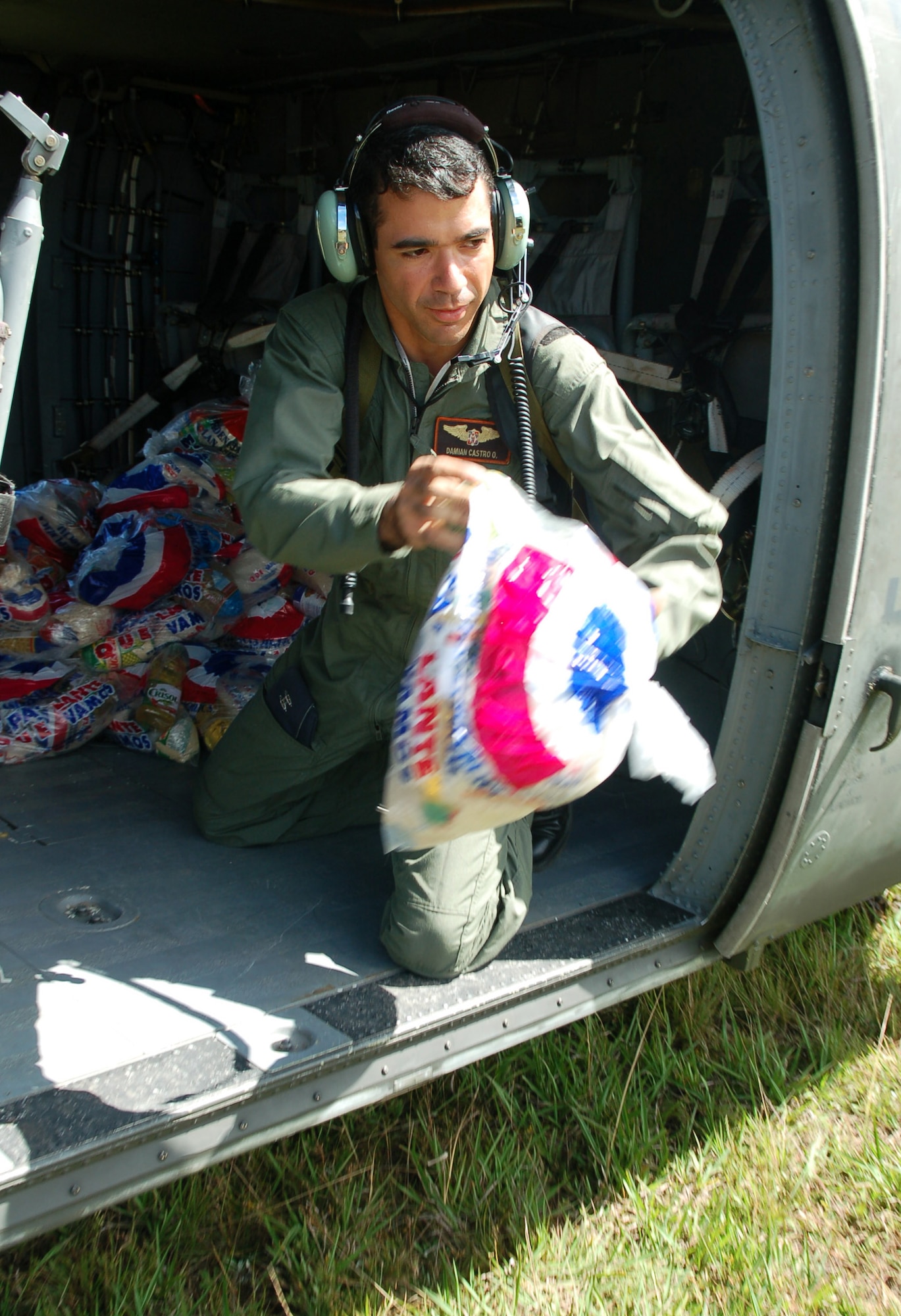 AZUA, Dominican Republic -- 1st Lt. Damian Castro, Dominican air force, tosses bags of food out of an idling UH-60 Black Hawk helicopter to local villagers during a food delivery Nov. 11.  As of Nov. 12, American and British aircrews had delivered more than 241,000 pounds of provisions to the island nation as part of a Combined, Joint, International relief effort following Tropical Storm Noel.  (U.S. Air Force photo by Staff Sgt. Austin M. May)