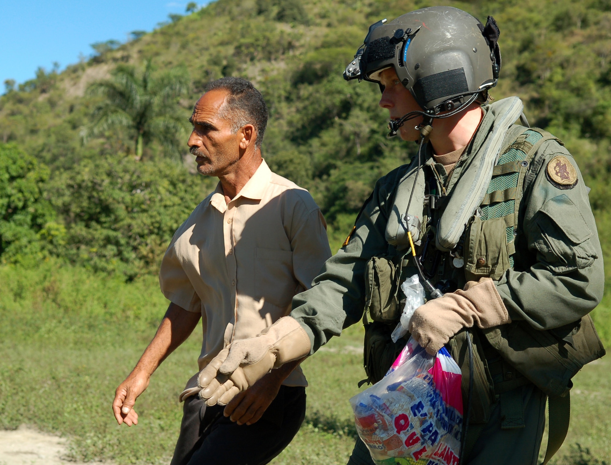 AZUA, Dominican Republic -- Army Specialist Ian Shaffer, a UH-60 crew chief with the 1st Battalion-228th Aviation Regiment deployed from Soto Cano Air Base, Honduras, asks a Dominican man to inform the people of his village safety precautions around an idling Black Hawk during a food delivery Nov. 11.  As of Nov. 12, American and British aircrews had delivered more than 241,000 pounds of provisions to the island nation as part of a Combined, Joint, International relief effort following Tropical Storm Noel.  (U.S. Air Force photo by Staff Sgt. Austin M. May)