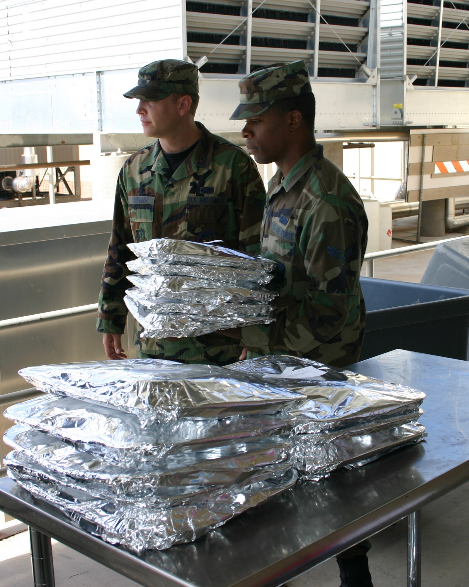 CANNON AIR FORCE BASE, N.M. - Airman 1st Class Bryan Karason, 27th Special Operations Mission Support Squadron, assists Airman 1st Class Marc Hightower, 27th Special Operations Component Maintenance Squadron, who is picking up his meals for his Meals on Wheels route. The Cannon Junior Enlisted Council volunteered one week a month to deliver meals for the local Clovis Meals on Wheels. (U.S. Air Force photo by Airman Elliott Sprehe)