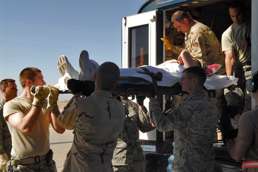 332nd Air Expeditionary Wing volunteers unload a patient from an ambulance bus and prepare to take the patient to a waiting C-17 Globemaster III at Balad Air Base, Iraq. Air Force Theater Hospital volunteers from throughout the base help the Contingency Aeromedical Staging Facility staff load and secure patients. The patient will then fly to Ramstein AB, Germany, to receive additional medical care at Landstuhl Regional Medical Center. (U.S. Air Force photo/Staff Sgt. Joshua Garcia) 