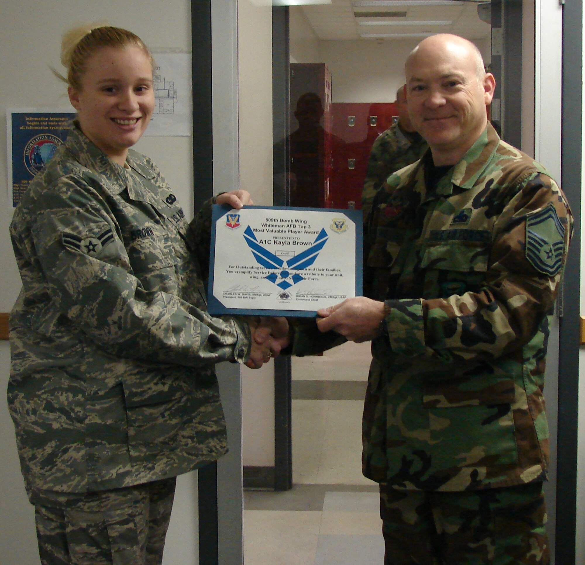 WHITEMAN AIR FORCE BASE, Mo. – Airman 1st Class Kayla Brown, 509th Maintenance Group, receives the Whiteman Top 3 Association Most Valuable Player Award Nov. 1 from Senior Master Sgt. Charles Davis, 509th Bomb Wing Top 3 president. Airman Brown was instrumental in the recent maintenance group information management consolidation. She spearheaded the electronic information management element by managing 64 file plans, ensuring accurate and complete records. She also volunteered numerous times at the Missouri Veterans Home in Warrensburg and donated more than 40 hours of her off duty time coaching and mentoring youth soccer athletes throughout the Whiteman youth program. In addition, she earned an estimated 15 credit hours towards her Community College of the Air Force degree in communications and information. The Top 3 MVP award is given each month to any staff sergeant or below throughout the wing. This is the Top 3's way to formally recognize an enlisted individual who epitomizes mission accomplishment, teamwork and esprit de corps for the men and women of the 509th Bomb Wing. (U.S. Air Force photo/Airman 1st Class Iesha Billingsley)