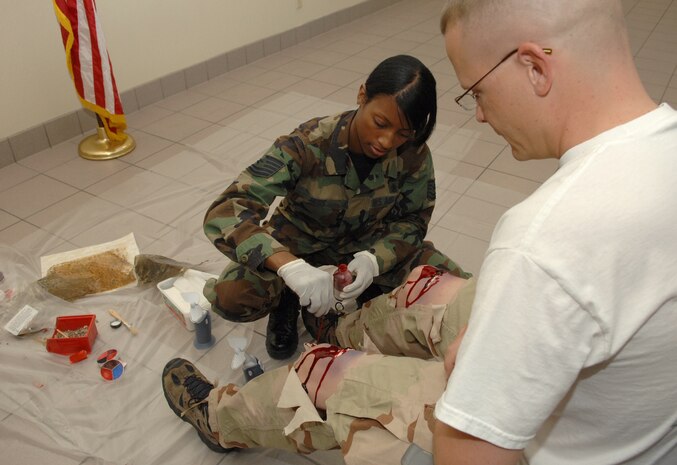 Tech Sgt Anita Russ, preventative health noncommissioned officer in charge, 99th Medical Operations Squadron, creates fake injuries on the legs of Tech. Sgt. Kevin Jacobs, information assurance officer with Detachment 1, 53rd Computer Systems Squadron, , in preparation for a major accident response exercise here on Nov. 5. The exercise, held in preparation for Nellis' air show, gave Nellis Airmen a chance to sharpen emergency response skills in the event of a mass casualty incident. (U.S. Air Force photo by Airman 1st Class Kasabyan D. McGarvey)