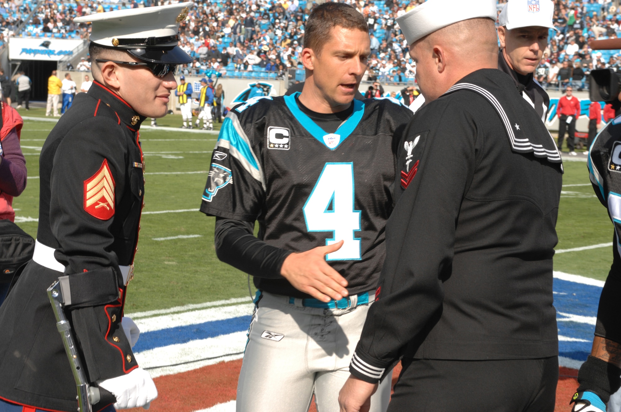 CHARLOTTE, N.C. -- Carolina Panthers kicker, John Kasay, shakes hands at mid-field with Navy Hospital Corpsman William Cooper and Marine Sgt. Edwin Bono Nov. 11. Bono and Cooper, injured in Iraq, were named honorary team captains in honor of Veterans Day. (U.S. Air Force photo/Staff Sgt. Henry Hoegen)