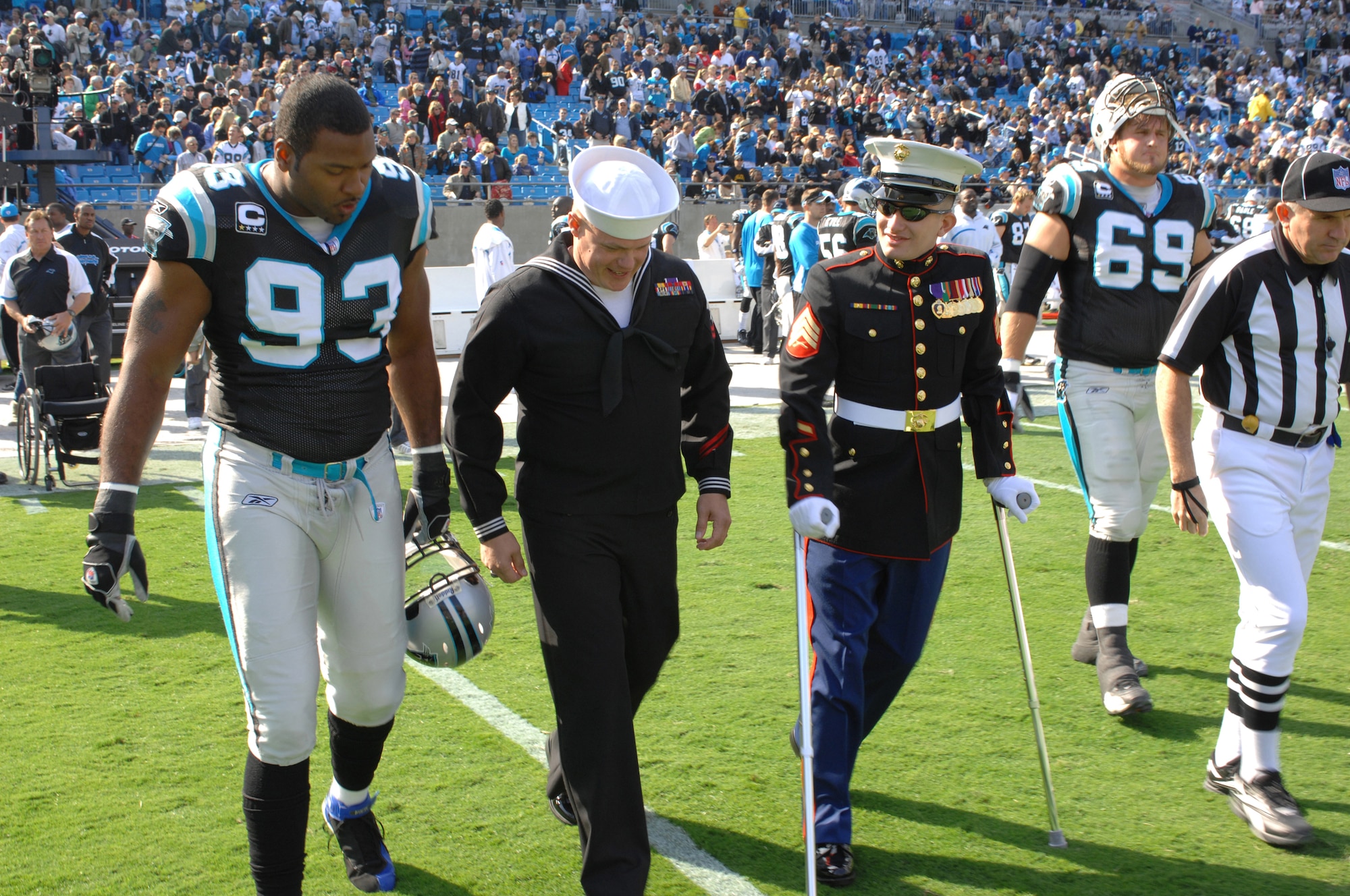 CHARLOTTE, N.C. -- Carolina Panthers defensive end, Michael Rucker, walks to mid-field Nov. 11 with Navy Hospital Corpsman William Cooper and Marine Sgt. Edwin Bono. Bono and Cooper, injured in Iraq, were named honorary team captains in honor of Veterans Day. (U.S. Air Force photo/Staff Sgt. Henry Hoegen)