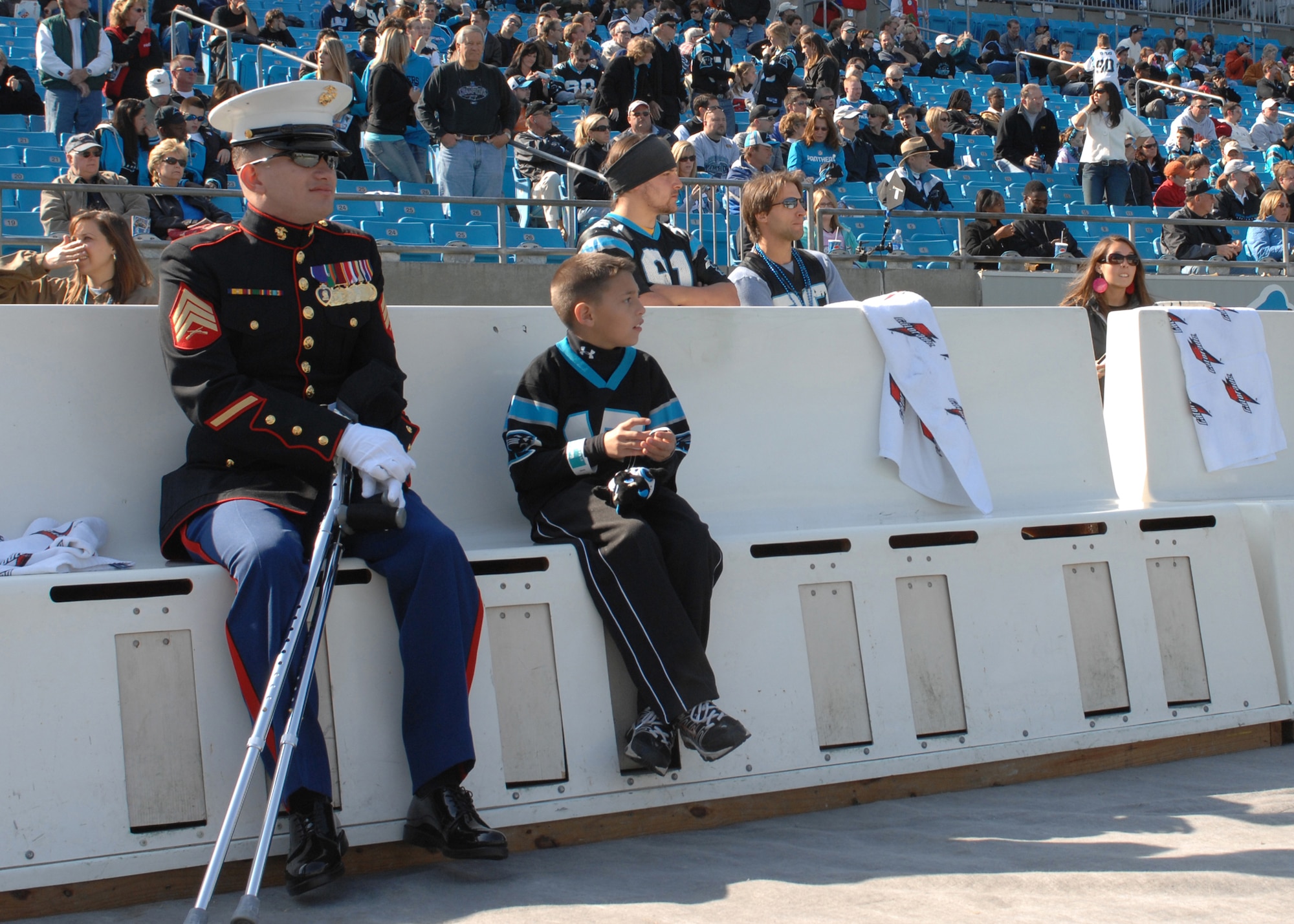 CHARLOTTE, N.C. -- Marine Staff Sgt. Edwin Bono sits on the Carolina Panthers bench with Michael, son of Navy Hospital Corpsman William Cooper, prior to the Panthers/Falcons game on Veterans Day Nov. 11. Bono and Cooper were injured in Iraq and named honorary team captains. (U.S. Air Force photo/Staff Sgt. Henry Hoegen)