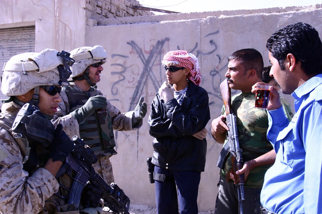 Sgt. Ysac M. Perez (left), a squad leader with Company K, 3rd Battalion, 5th Marine Regiment, Regimental Combat Team 6, stops to speak with Iraqi police while on patrol through the Andaloos District of Fallujah, Iraq, Nov. 15. Victor (second from left), the interpreter with Co. K, translated for both Perez and the IPs as they discussed reopening a road for vehicular traffic that had been closed for many months for security reasons. Having a Middle Eastern native, such as Victor, is a great help to the Marines for overcoming the language barrier and explaining cultural matters.